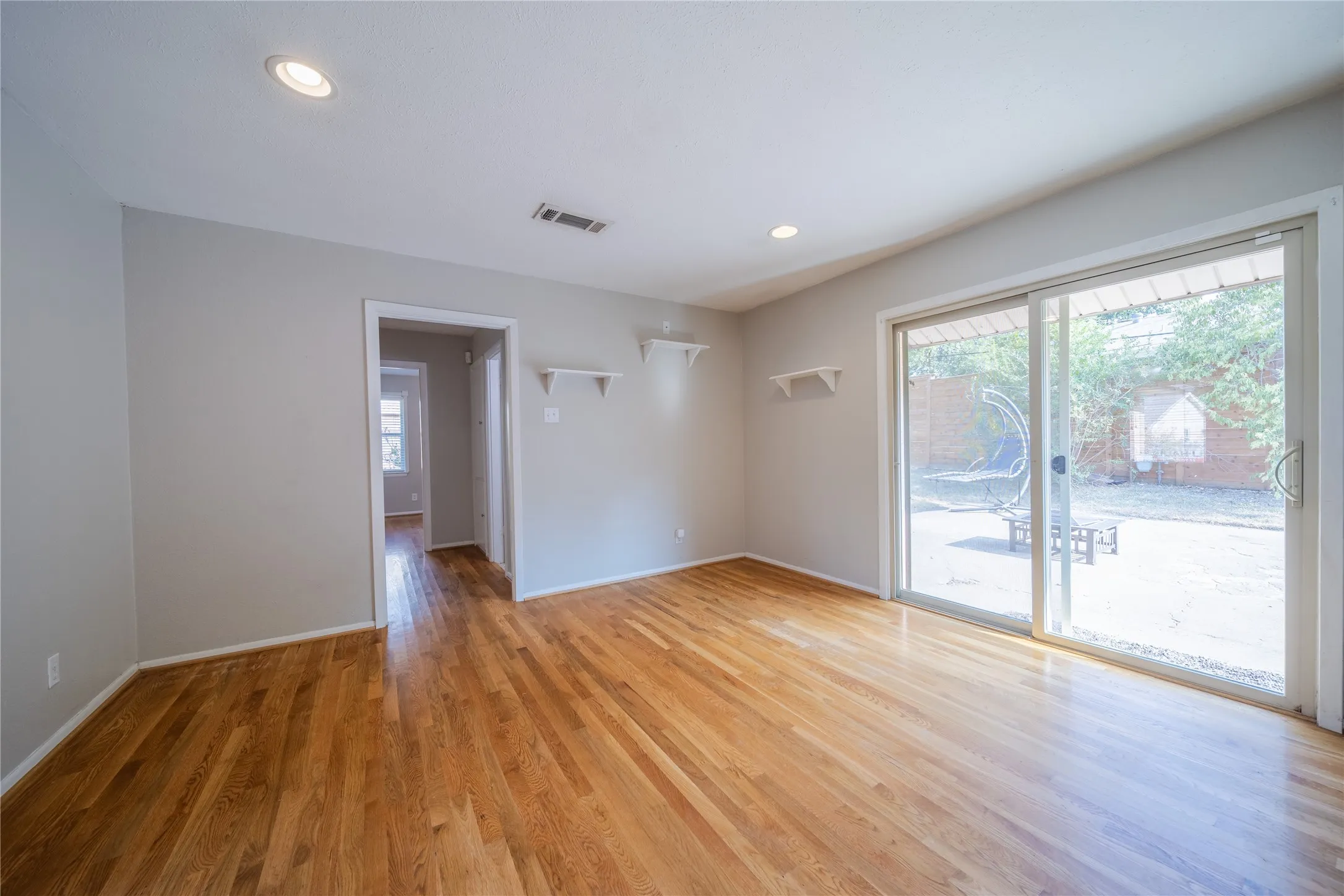 The spacious dining room has views to the back yard through sliding glass doors.  The door in the center of the photo leads to the hallway connecting all three bedrooms and the hall bathroom.