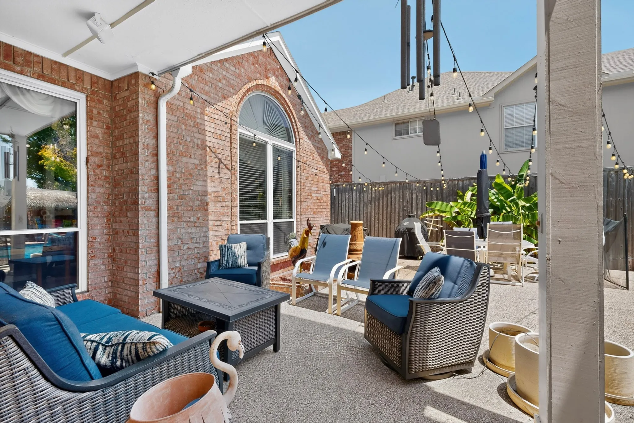 Brick exterior with a covered patio, arched window, and string lighting