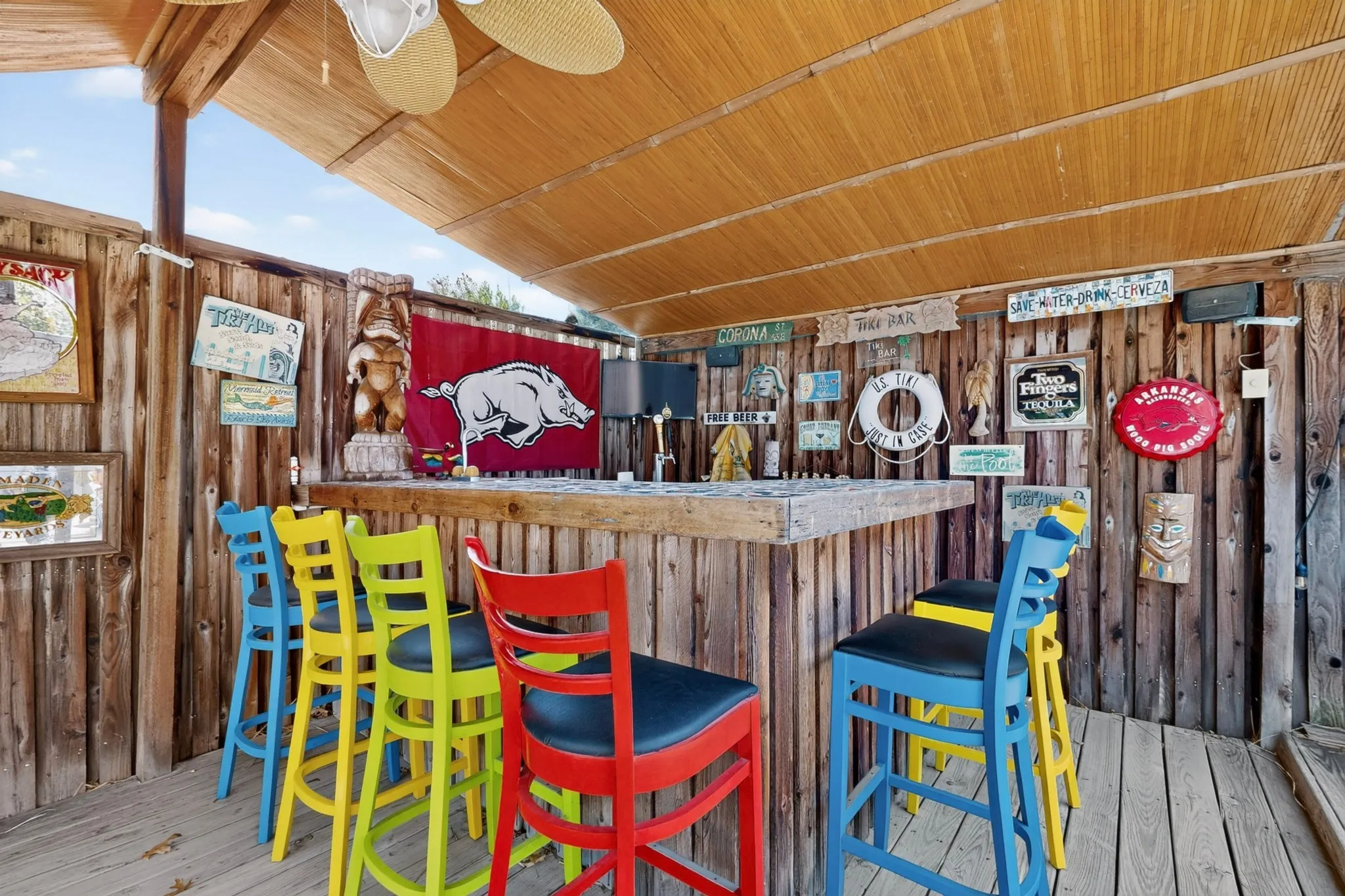 Outdoor cabana bar area featuring a wood-plank counter, wood-paneled walls, a slatted wood ceiling, and an overhead ceiling fan