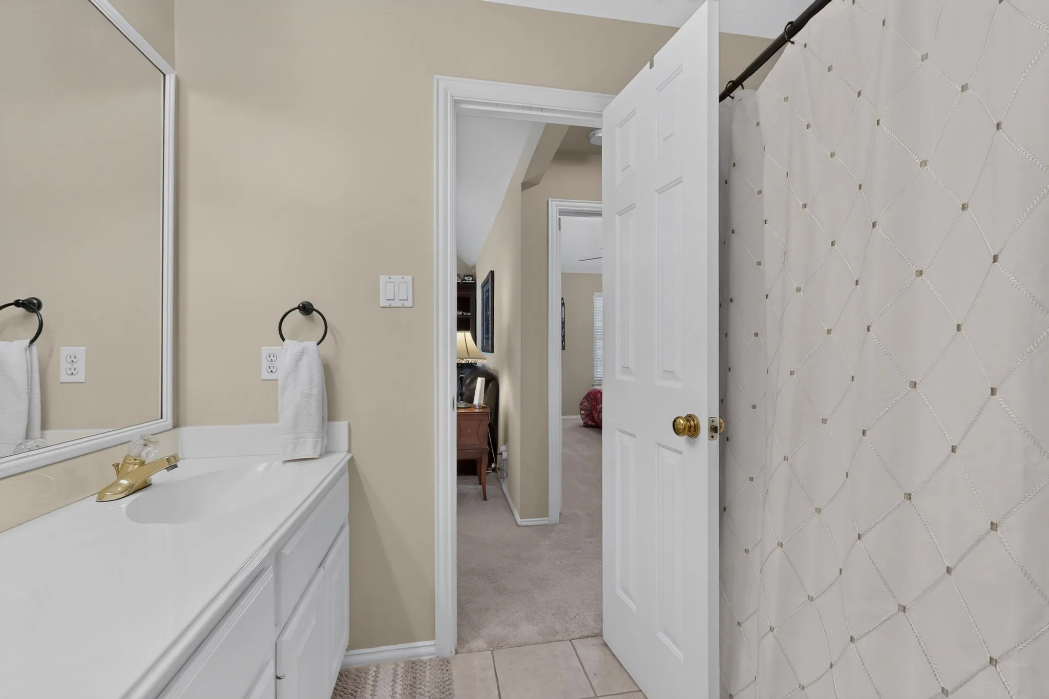 White vanity with integrated sink, framed mirror, and brushed brass faucet