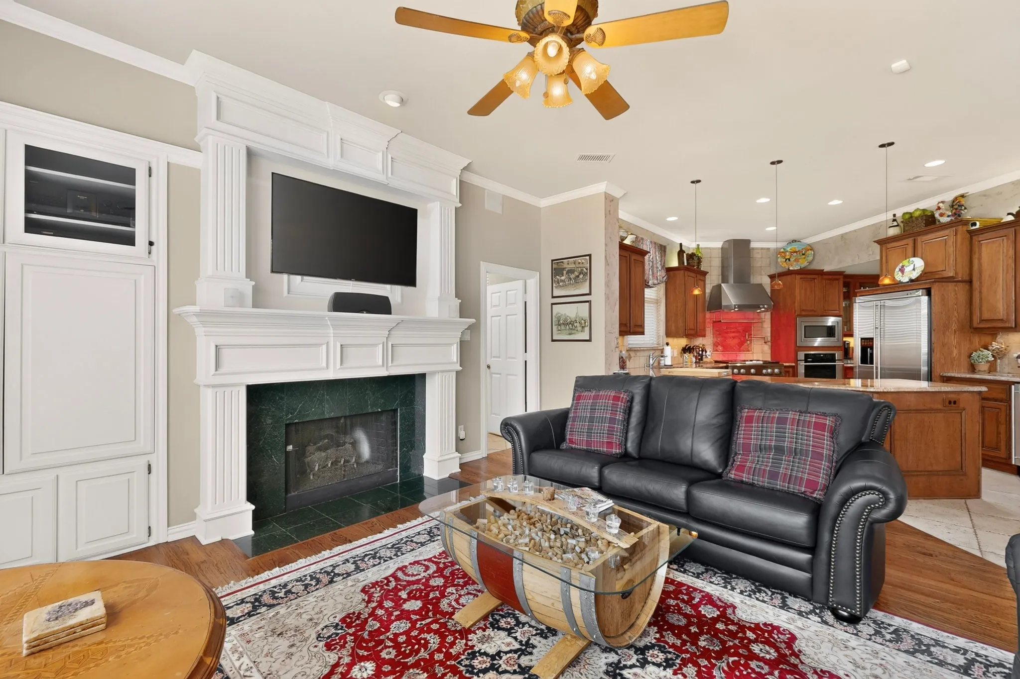 Built-in entertainment center with fireplace, custom white millwork, wood-finish flooring, and crown molding
