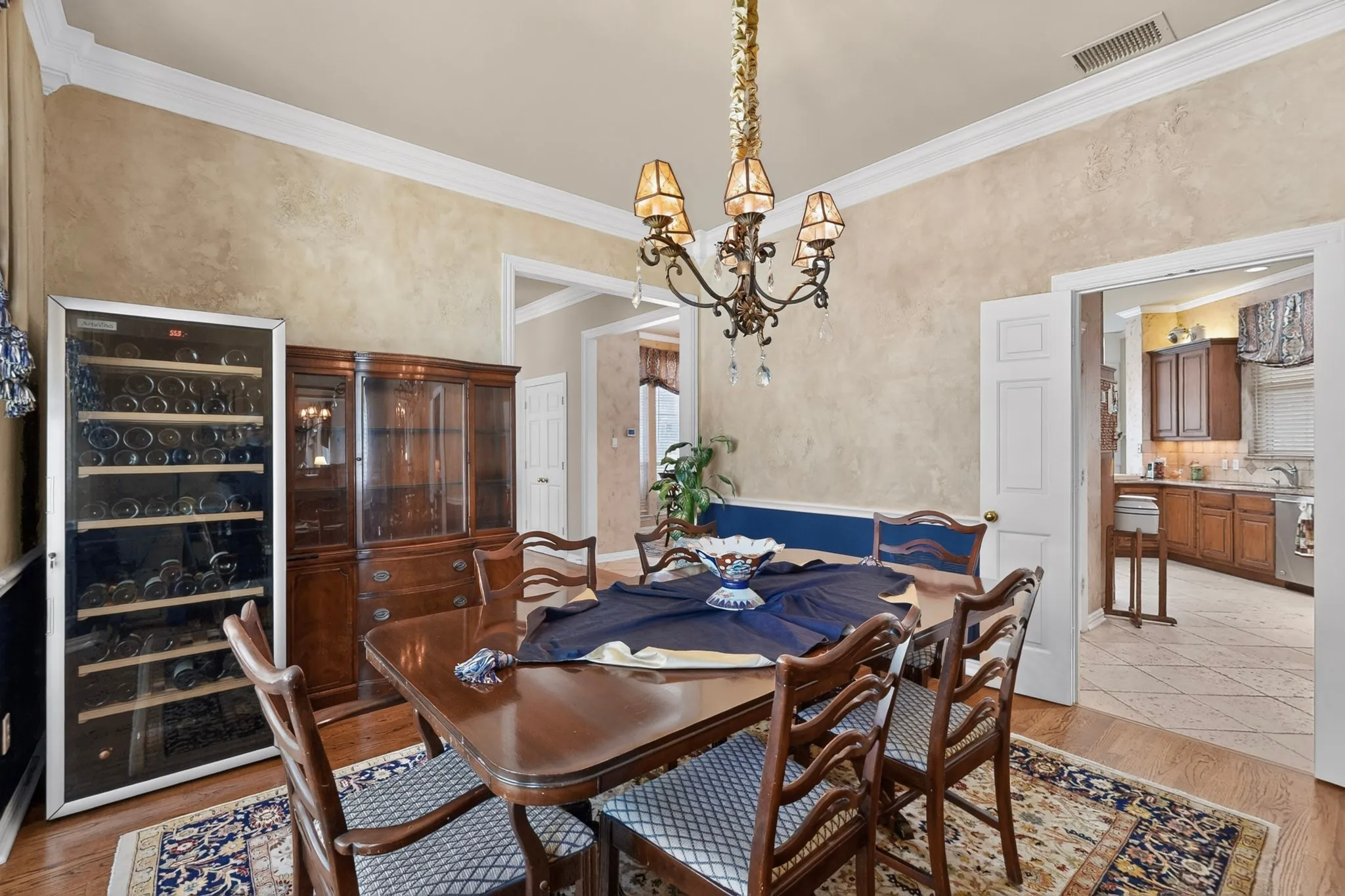 Hardwood flooring, crown molding, and a decorative chandelier illuminate this space