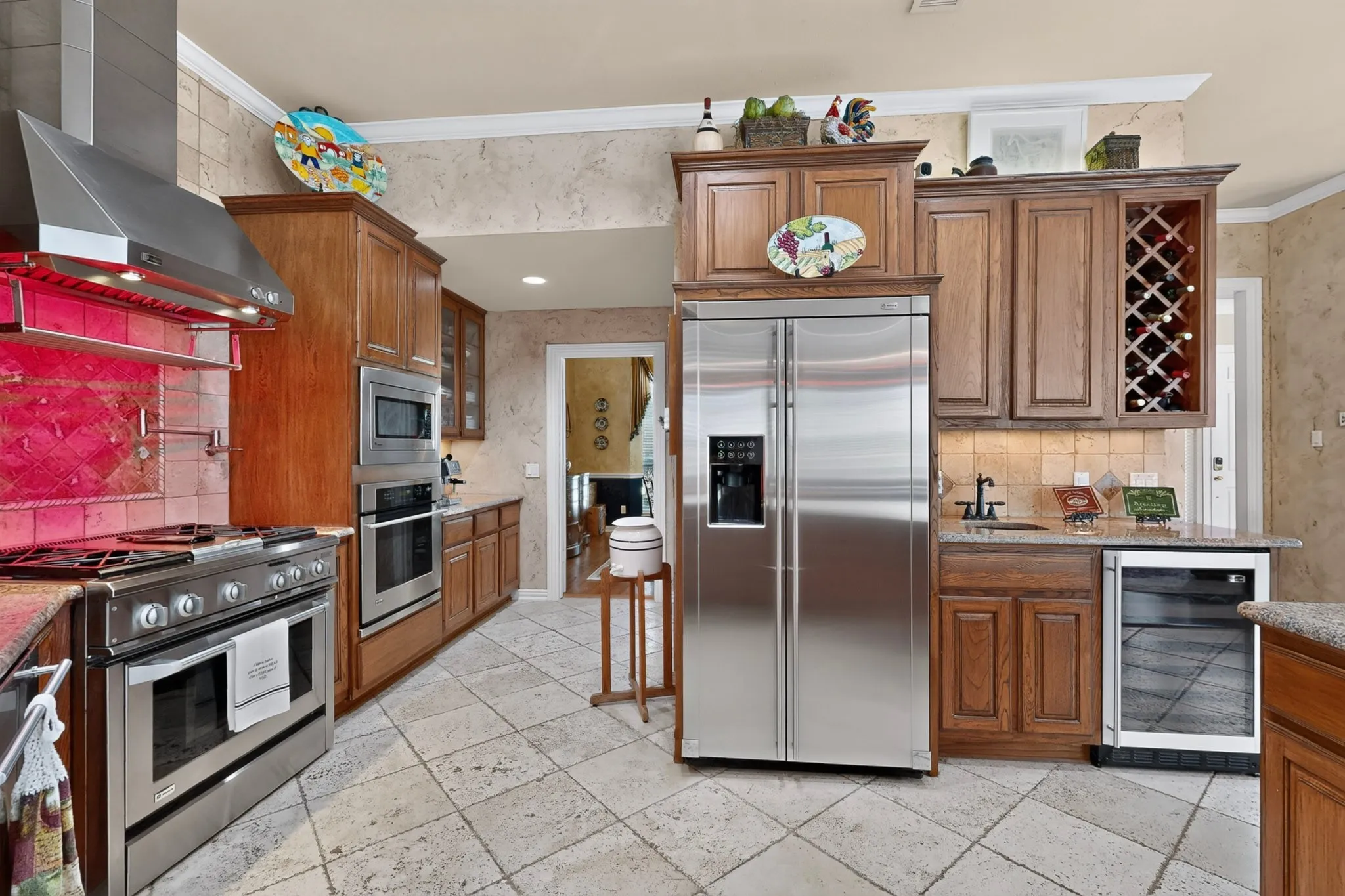 Gourmet kitchen featuring stainless steel appliances, a built-in wine rack, a beverage cooler, and extensive wood cabinetry