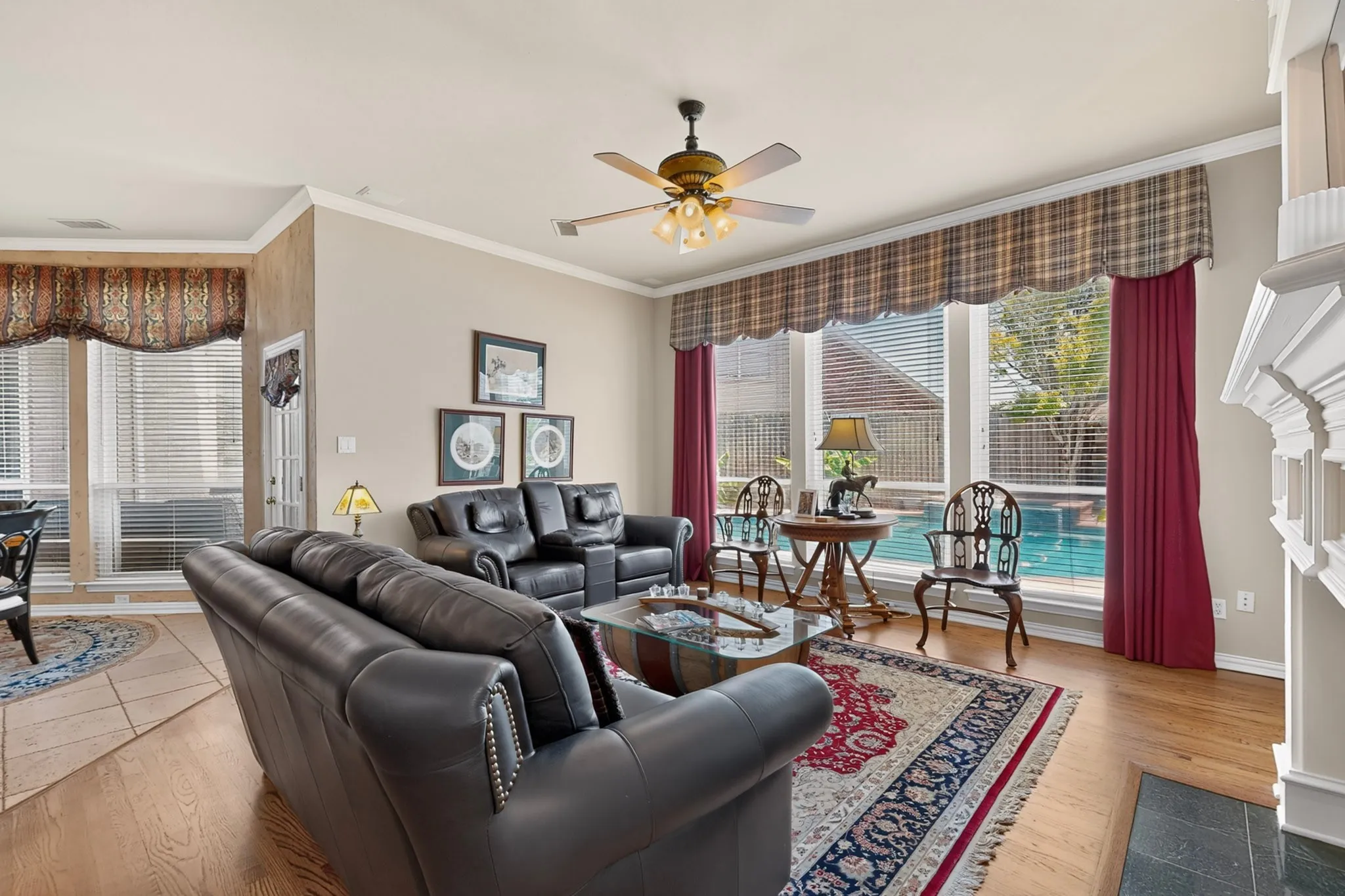 Warm interior featuring wood-finish flooring, a ceiling fan with integrated lighting, and crown molding