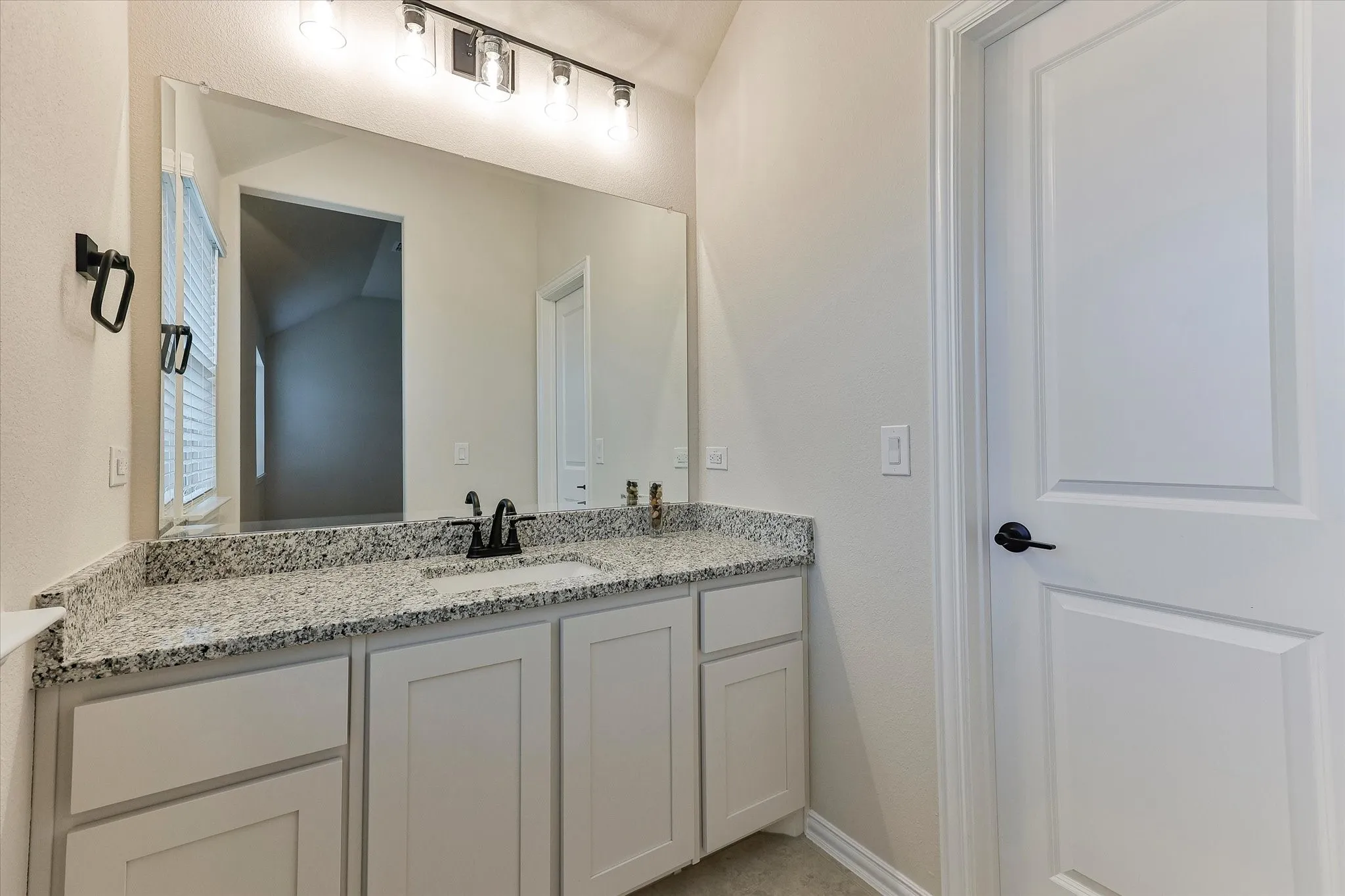 White vanity with shaker-style cabinetry, a drop-in sink, and a speckled countertop