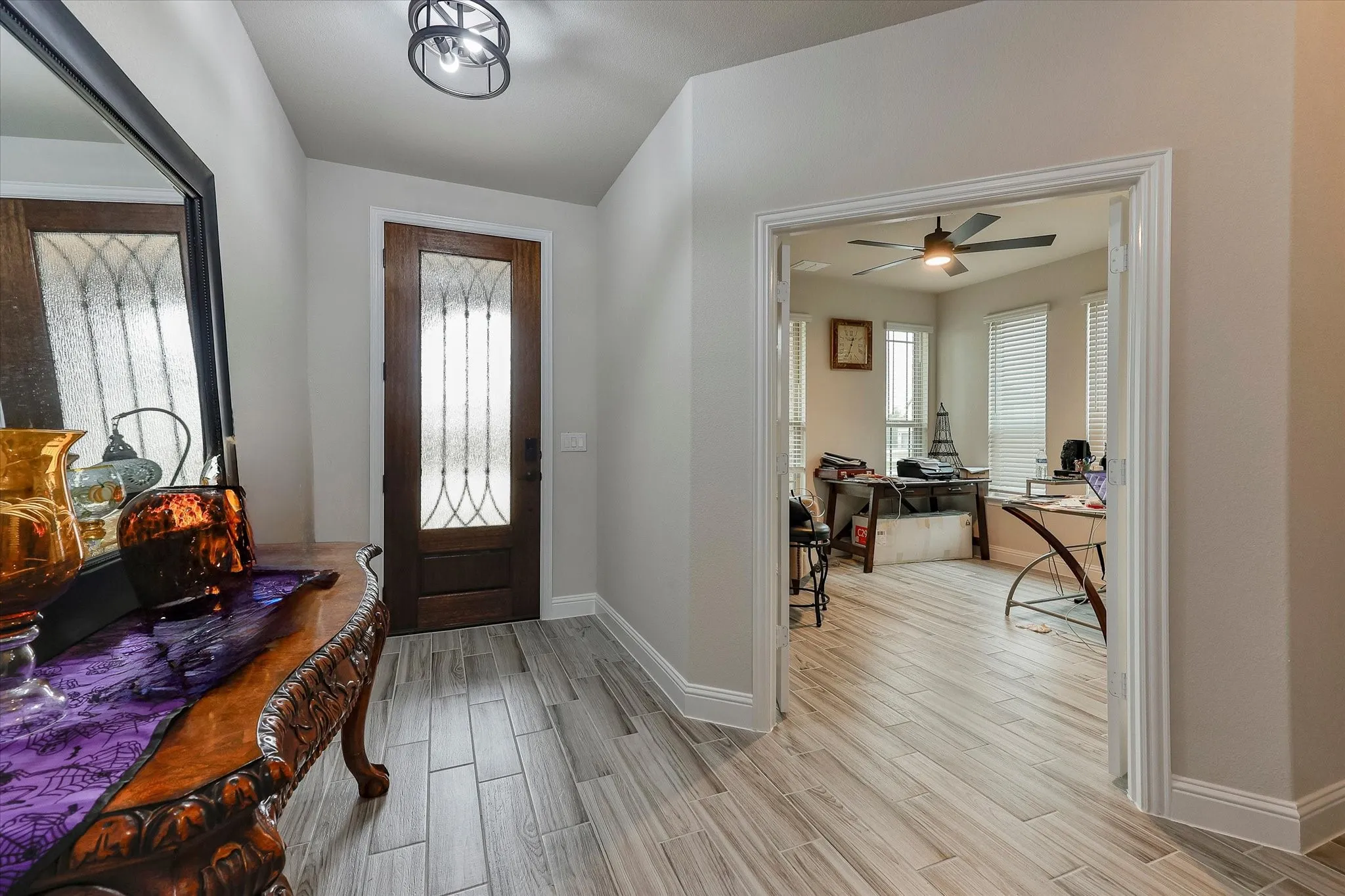 Entryway featuring wood-finish flooring, a dark wood entry door with decorative glass, and a modern ceiling light fixture
