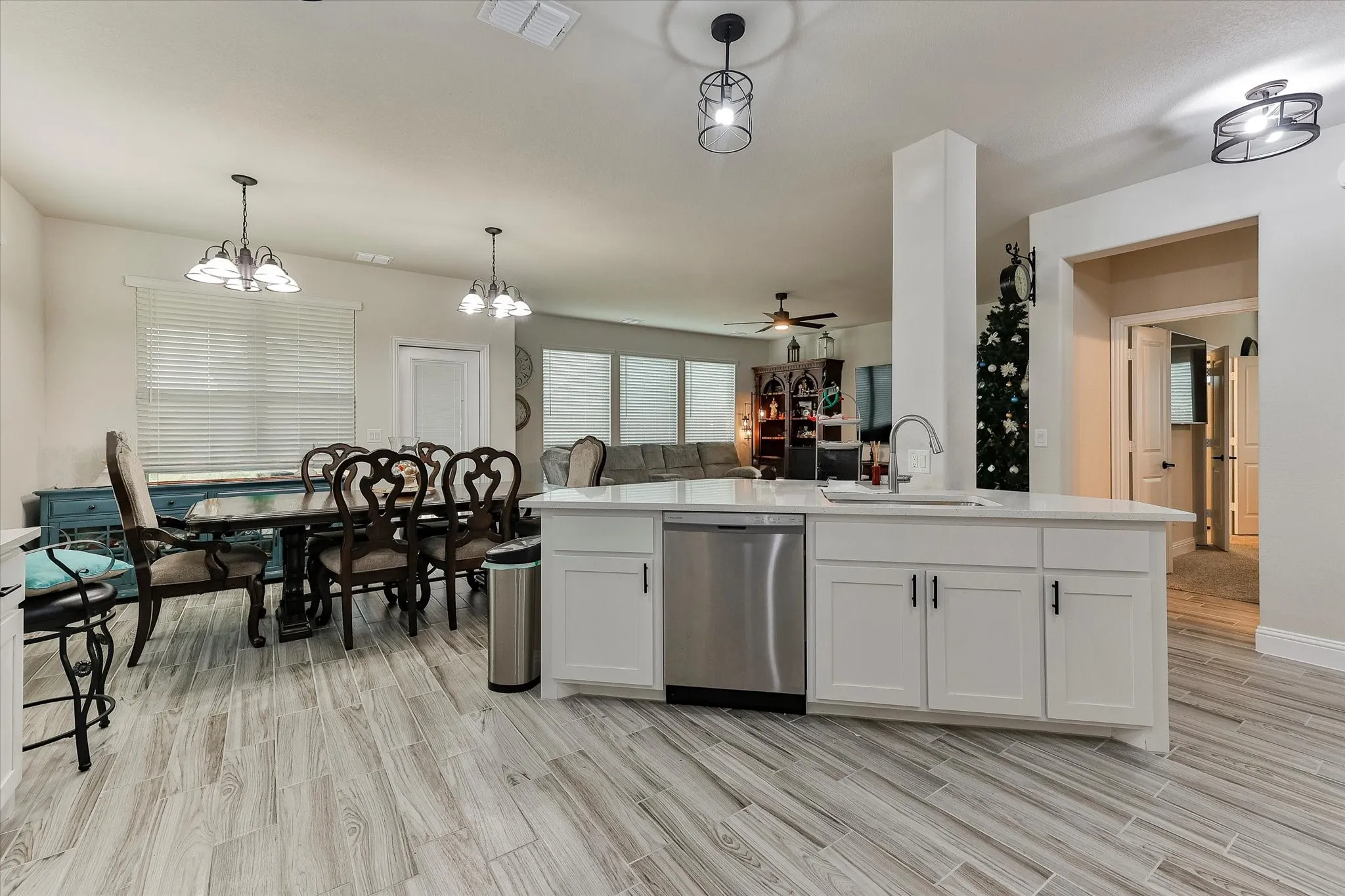 Kitchen island with a stainless steel dishwasher, white cabinetry, and a single-basin sink