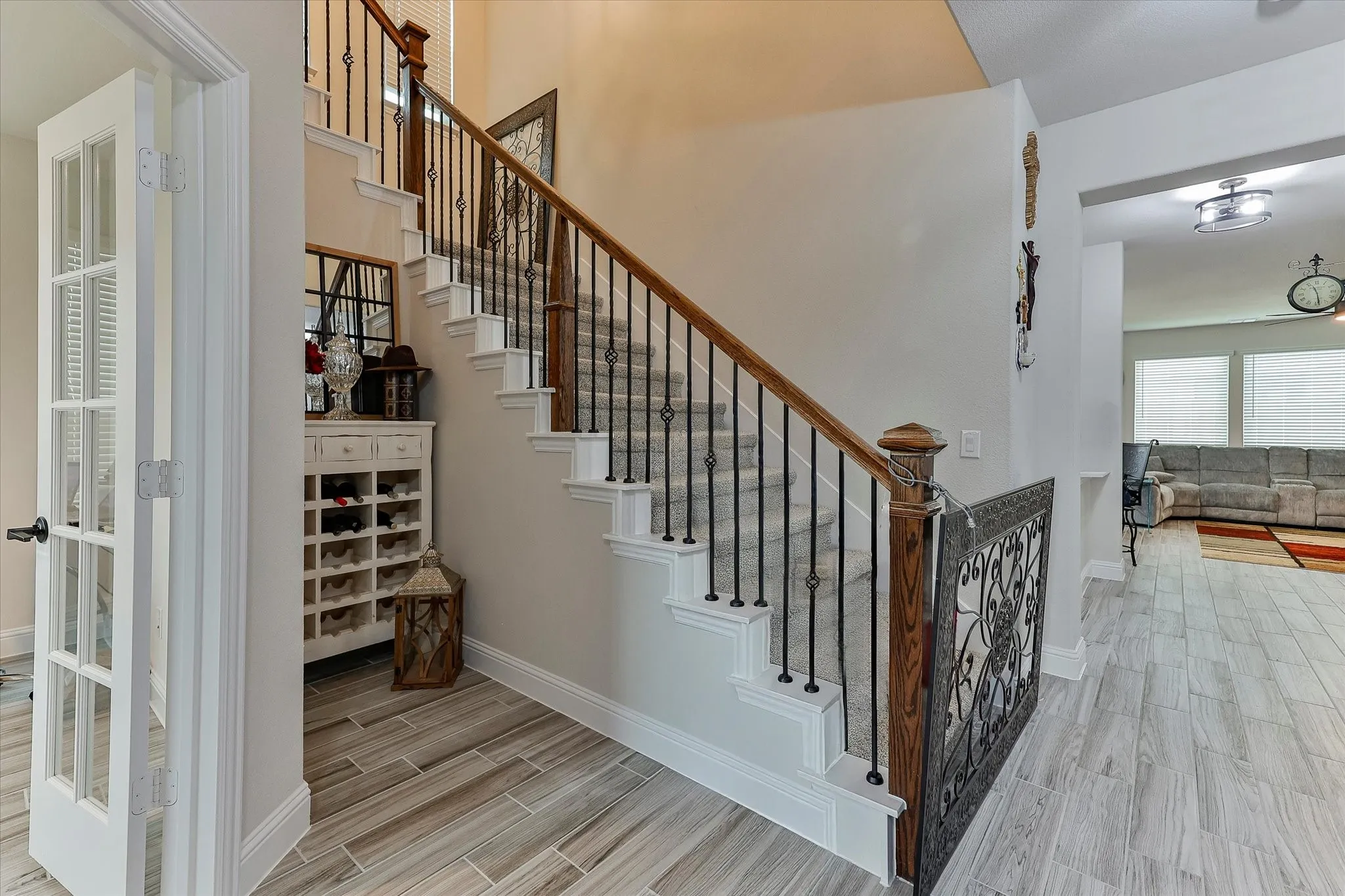 Staircase featuring wood handrail, wrought iron balusters, and carpeted treads