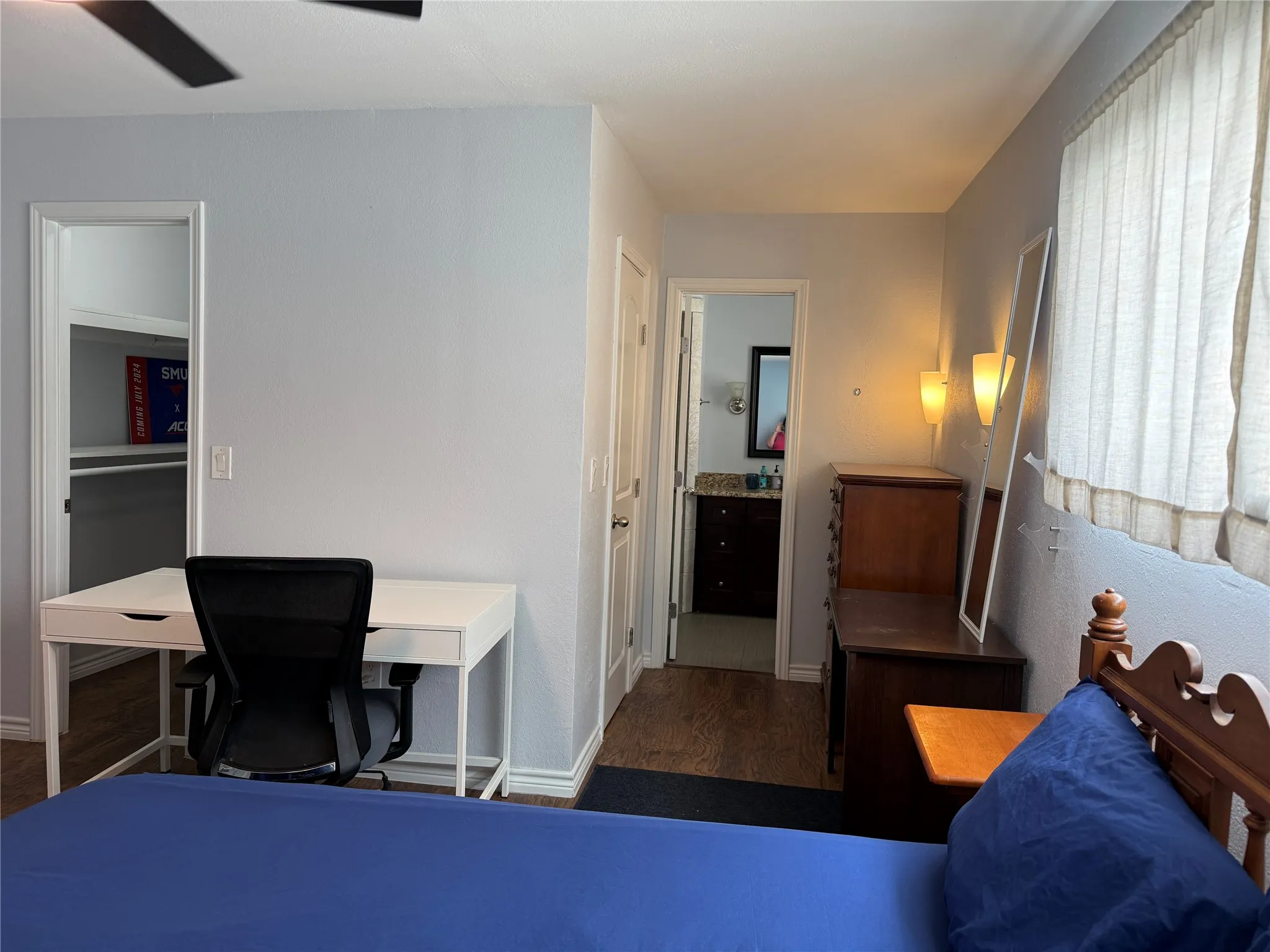 Bedroom featuring wood-finish flooring, a ceiling fan, and a window with curtains
