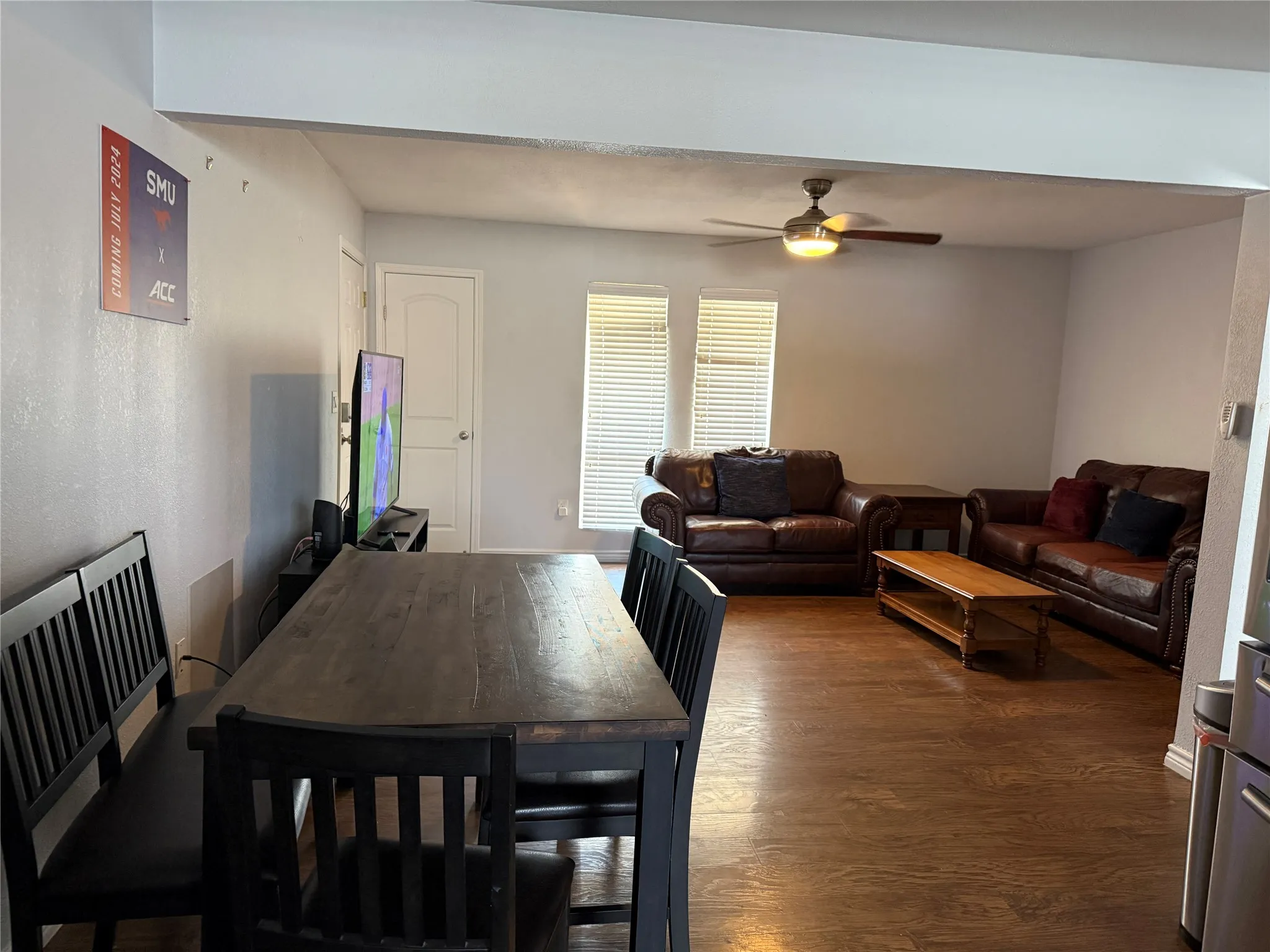 Open concept living area featuring wood-finish flooring, white walls, and a ceiling fan with integrated lighting