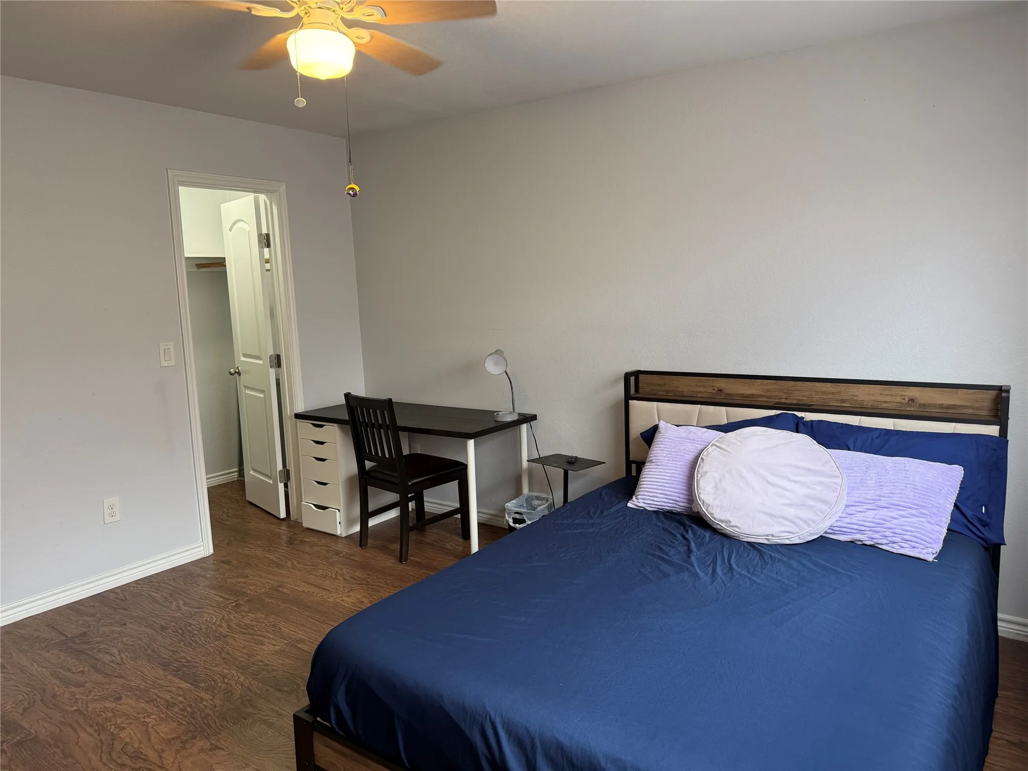 Bedroom featuring wood-finish flooring, a ceiling fan with integrated lighting, and a closet with a white paneled door