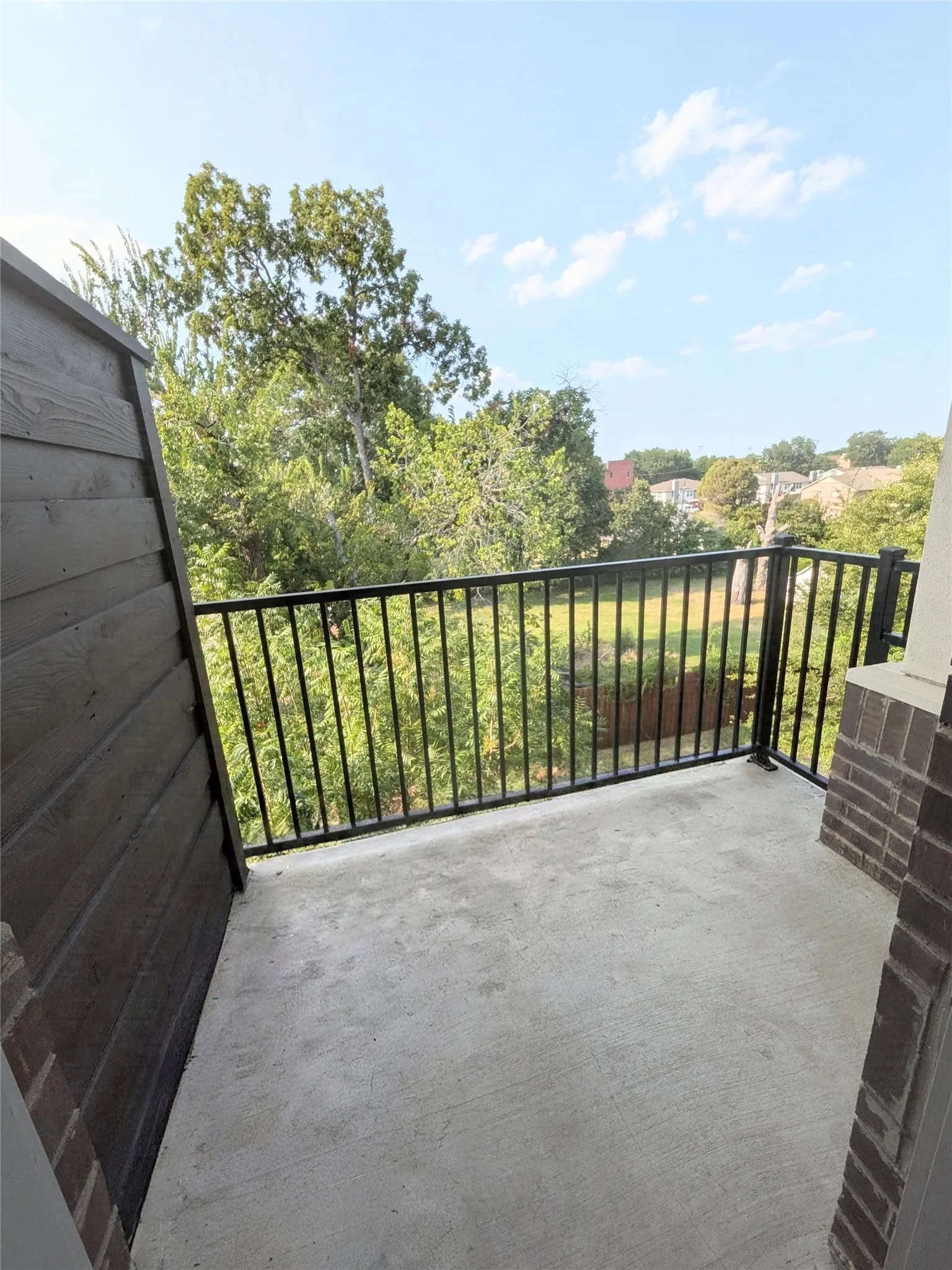Private primary room en-suite balcony featuring a concrete floor, black metal railing, and a slatted exterior wall