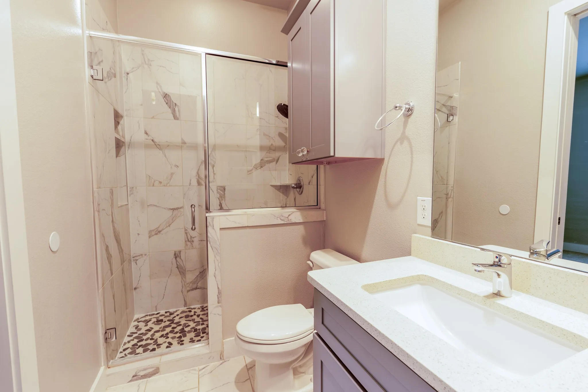 Contemporary en-suite 1st floor bathroom featuring a walk-in shower with a glass enclosure, large format tile, and a pebble floor