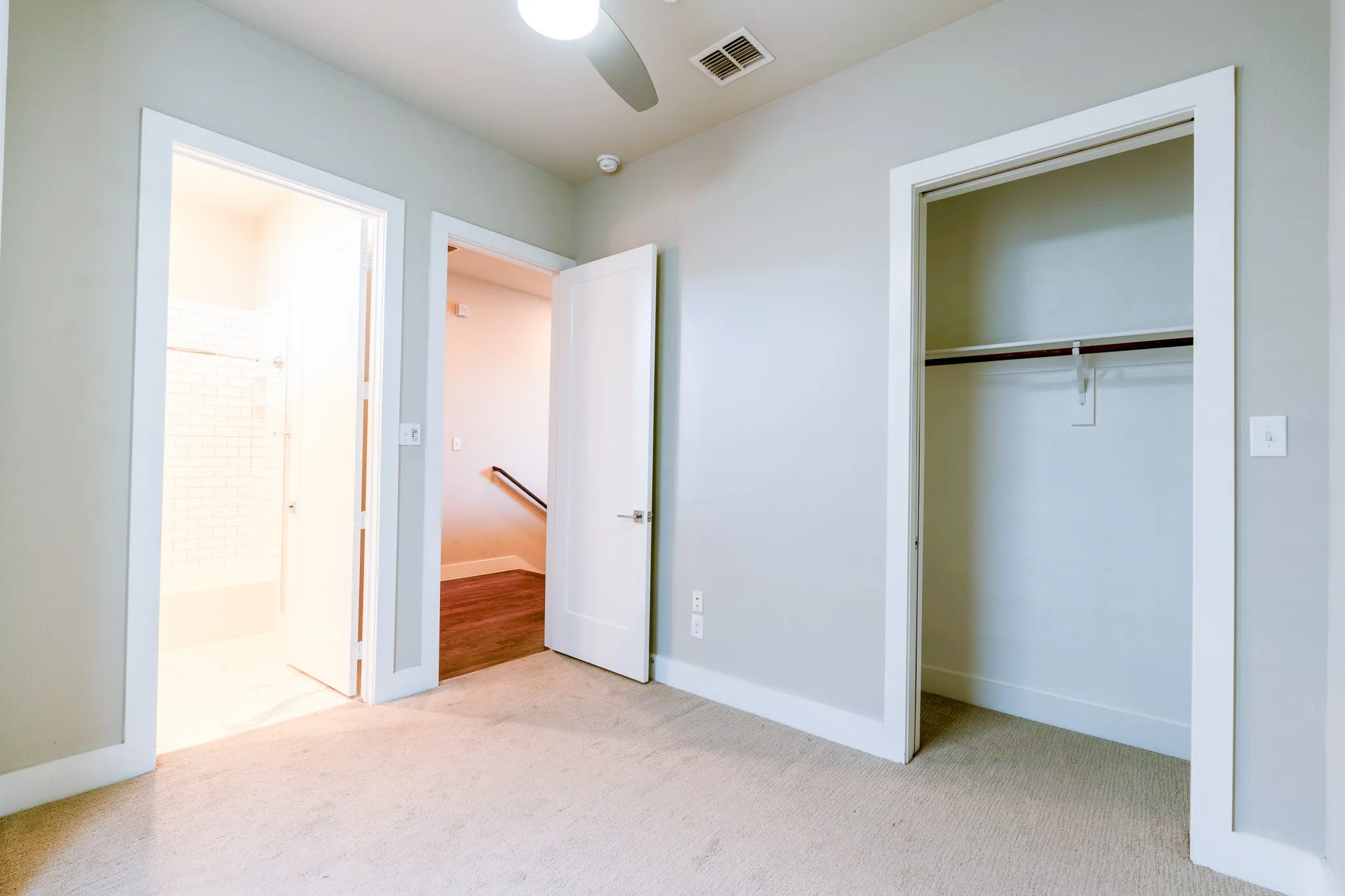 Carpeted room with light gray walls, a ceiling fan, and a recessed vent