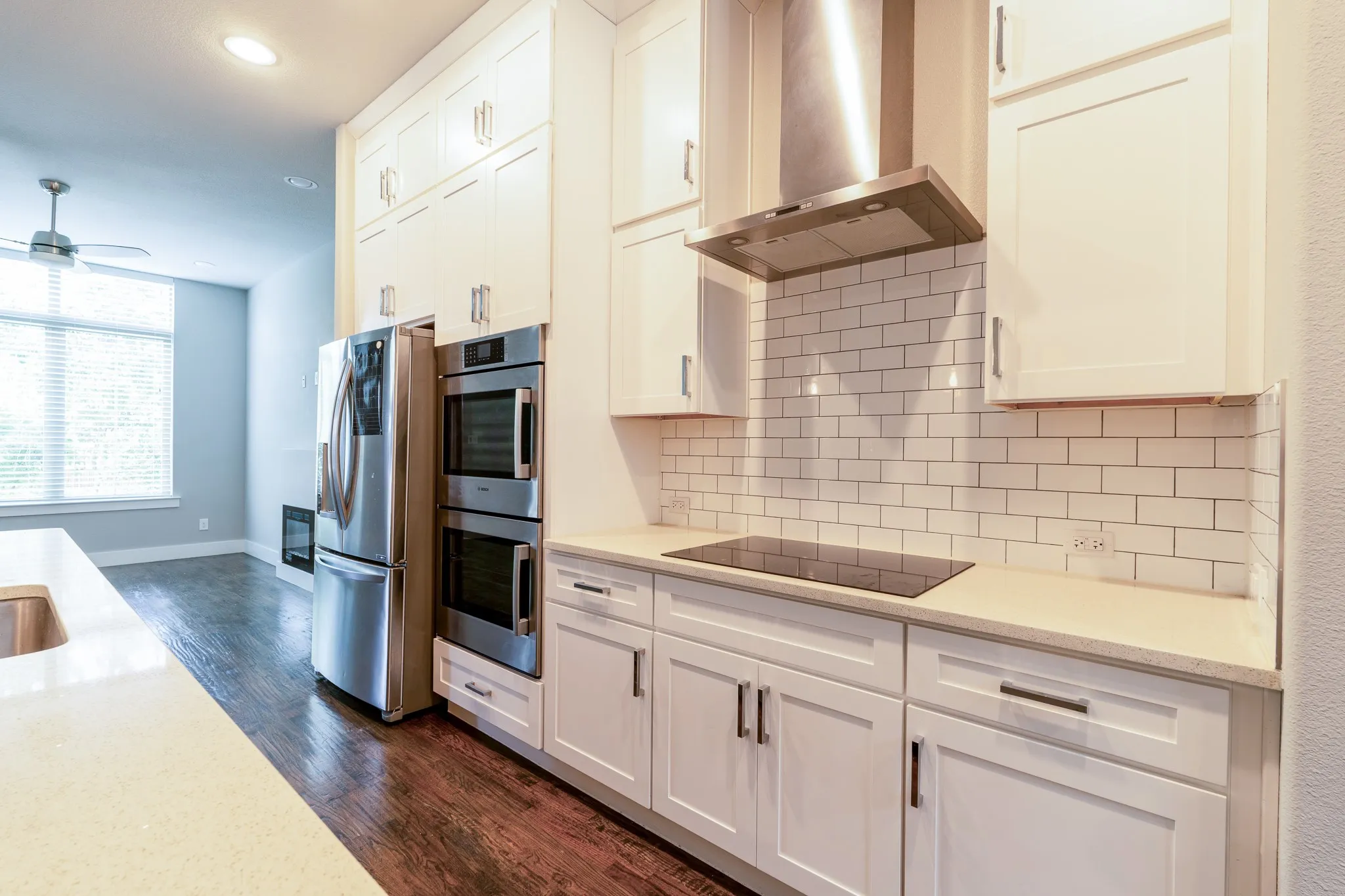 Modern kitchen featuring white shaker cabinetry, stainless steel appliances, a subway tile backsplash, and light-toned quartz countertops