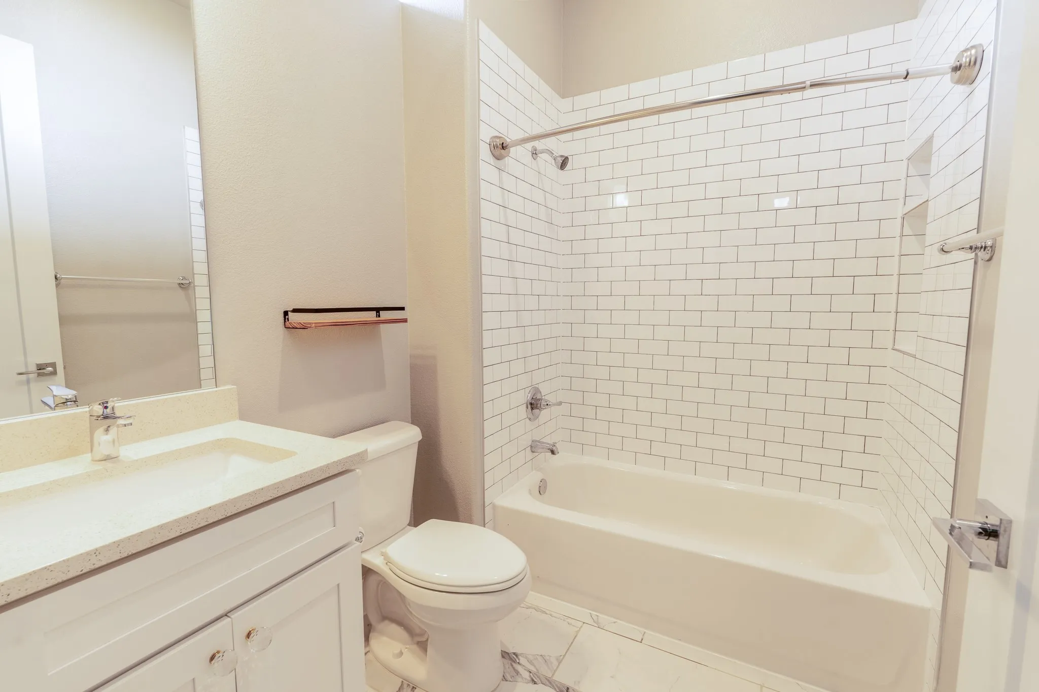 Second bedroom en-suite bathroom with quartz countertop, a white subway tile shower surround and a built-in niche