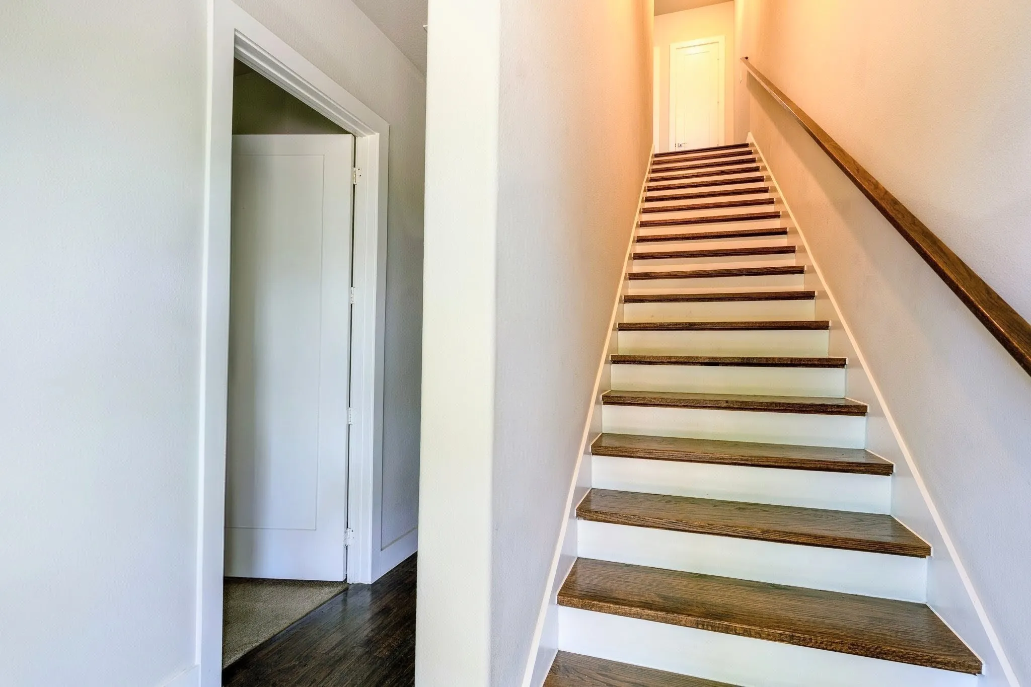 Entryway Staircase featuring wood-finish treads and white risers, complemented by a wood-finish handrail. 1st Floor Bedroom