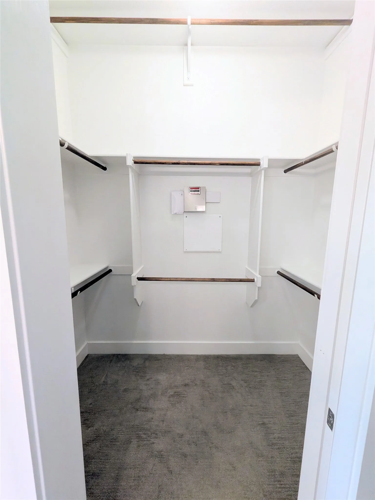 Primary bathroom walk-in closet featuring white walls, baseboards, and shelving
