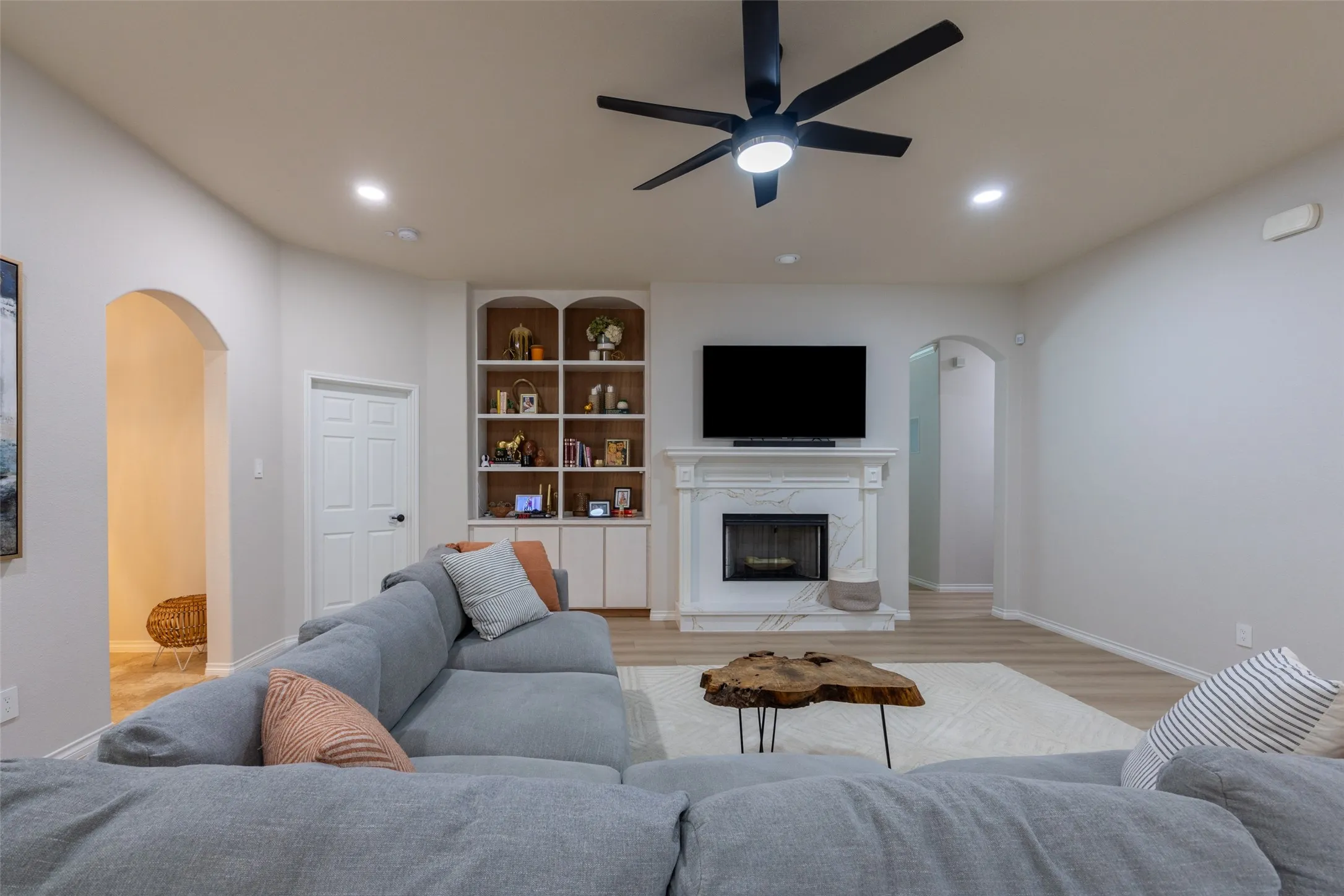 Recessed lighting, wood-finish flooring, built-in shelving, arched doorways, and a ceiling fan