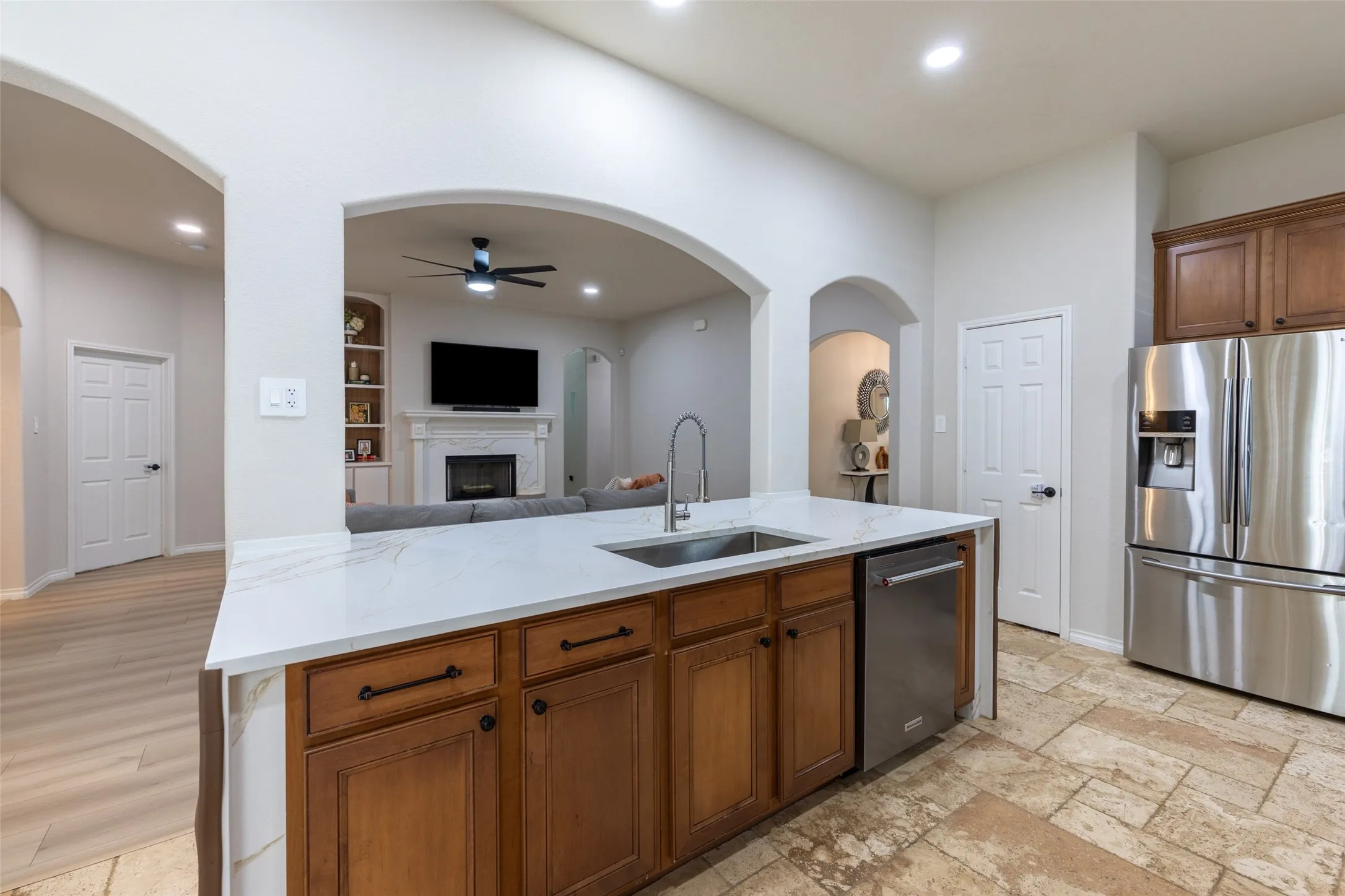Kitchen island with a solid surface countertop, stainless steel sink, and wood cabinetry