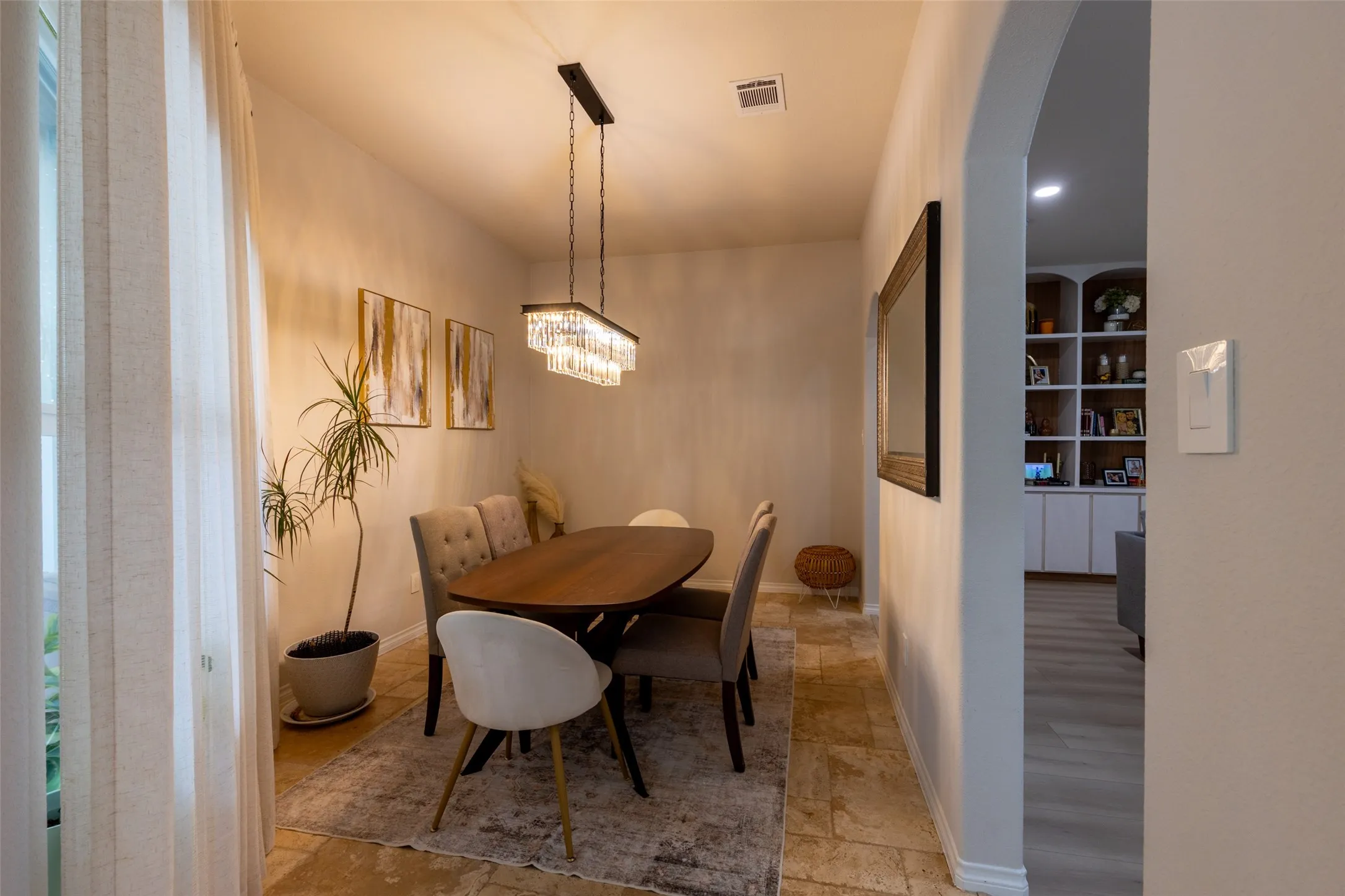 Tray ceiling with a crystal chandelier, arched doorway, and built-in shelving