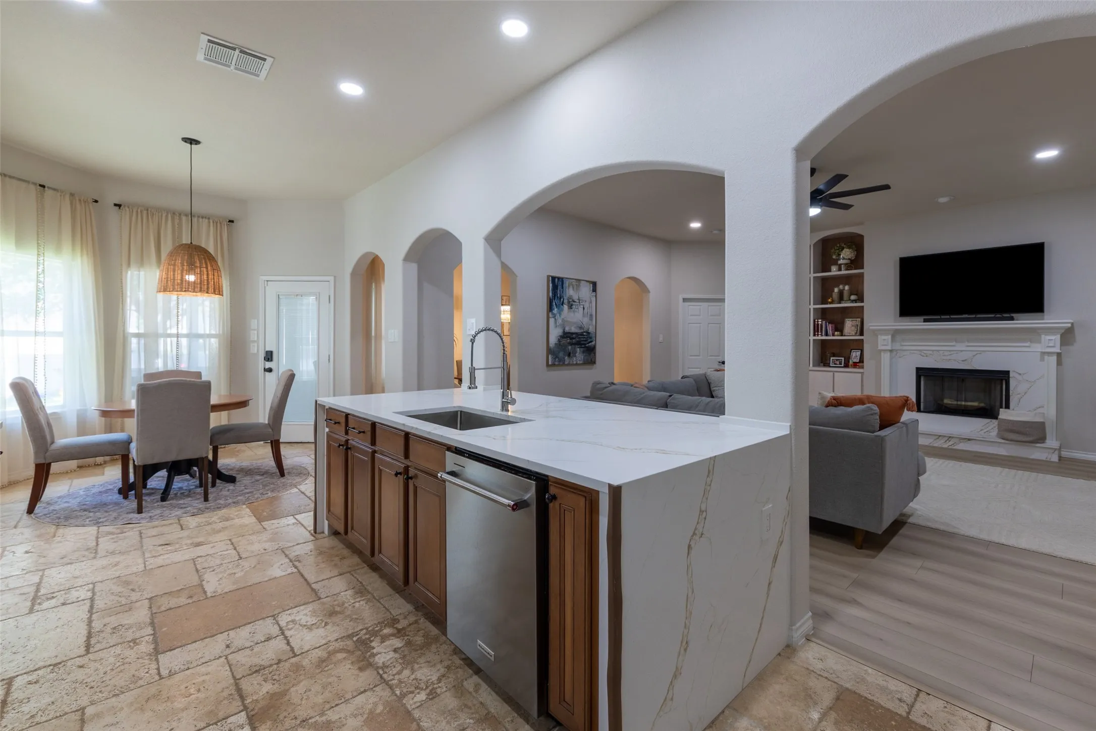 Spacious kitchen island with waterfall countertop, stainless steel sink, and integrated dishwasher