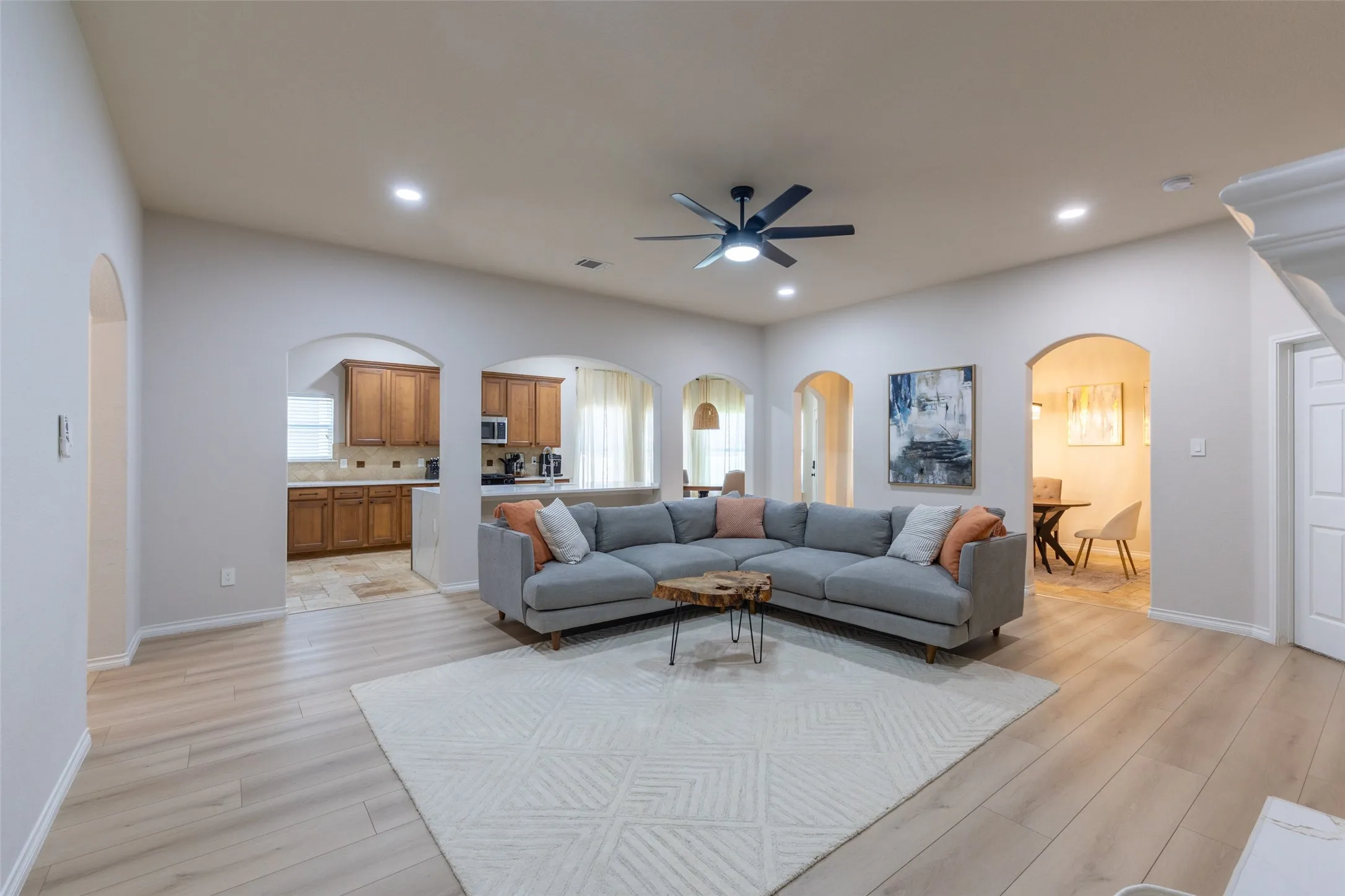 Archways with light-toned walls, wood-finish flooring, recessed lighting, and a ceiling fan with integrated lighting