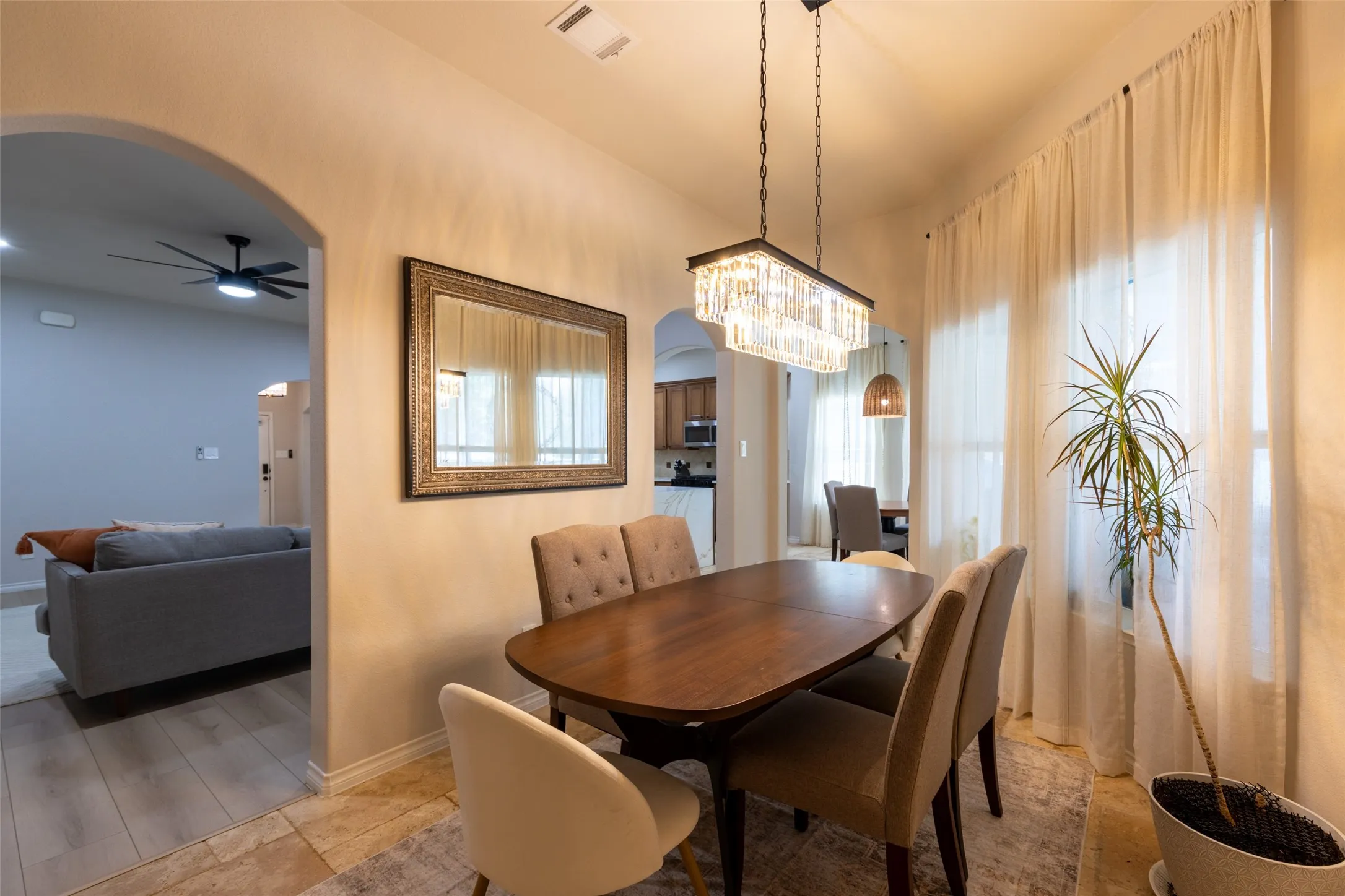 Arched doorway, rectangular crystal chandelier, decorative framed mirror, and sheer window coverings