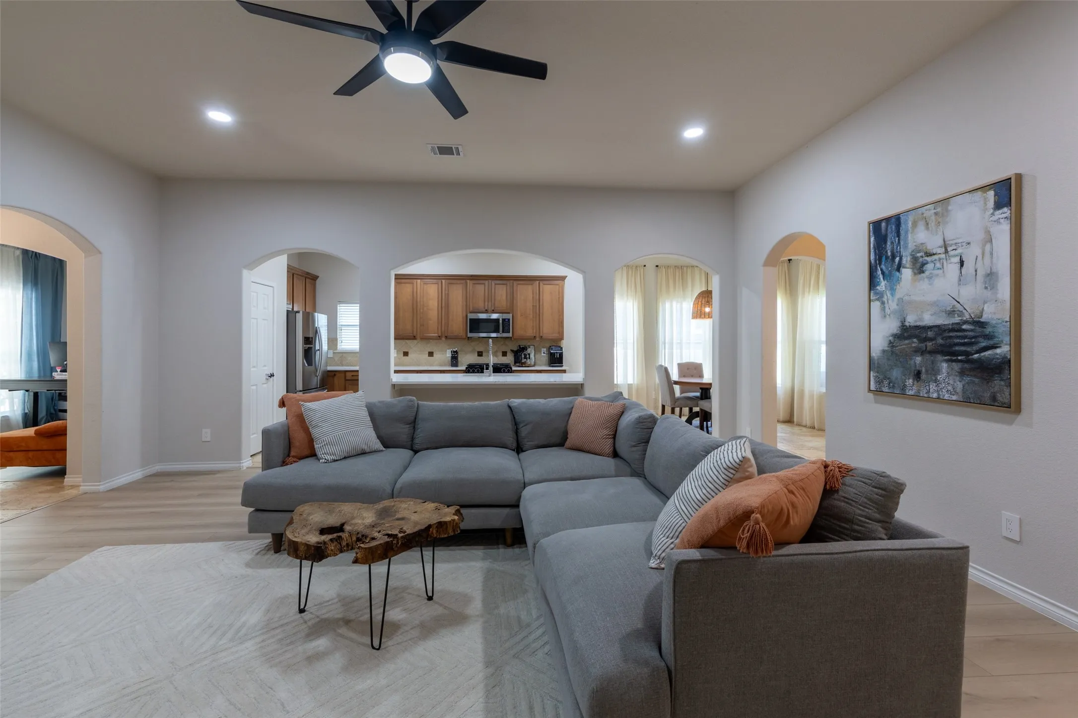 Spacious living area featuring light-toned flooring, recessed lighting, and a ceiling fan