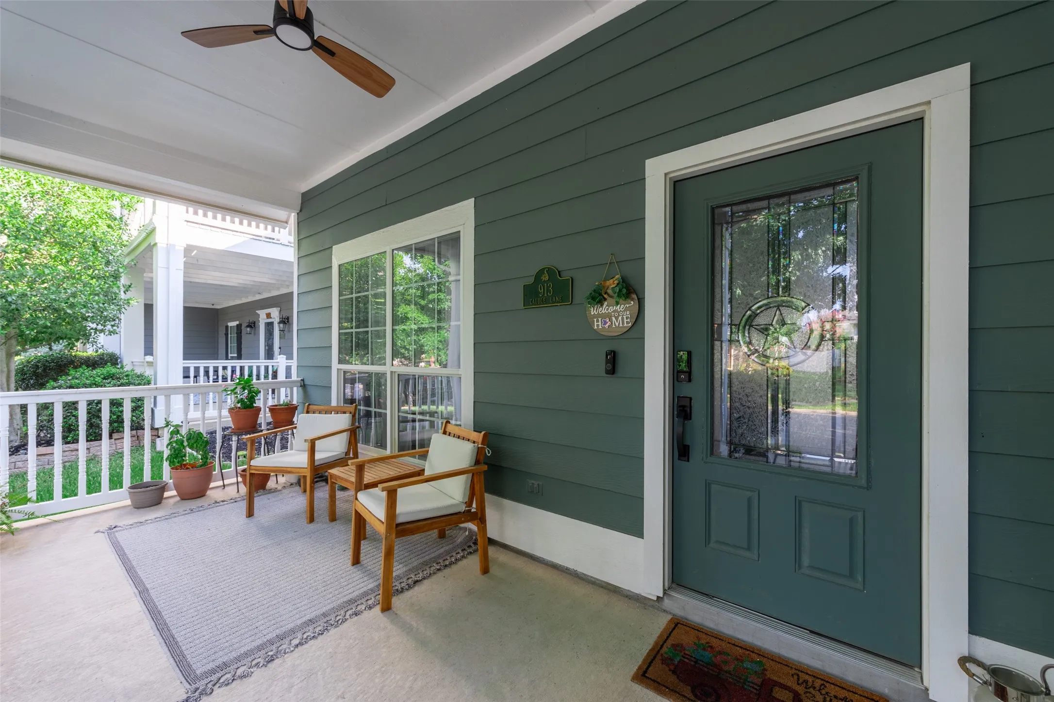Covered front porch with a ceiling fan, horizontal siding, and a decorative glass-paneled entry door
