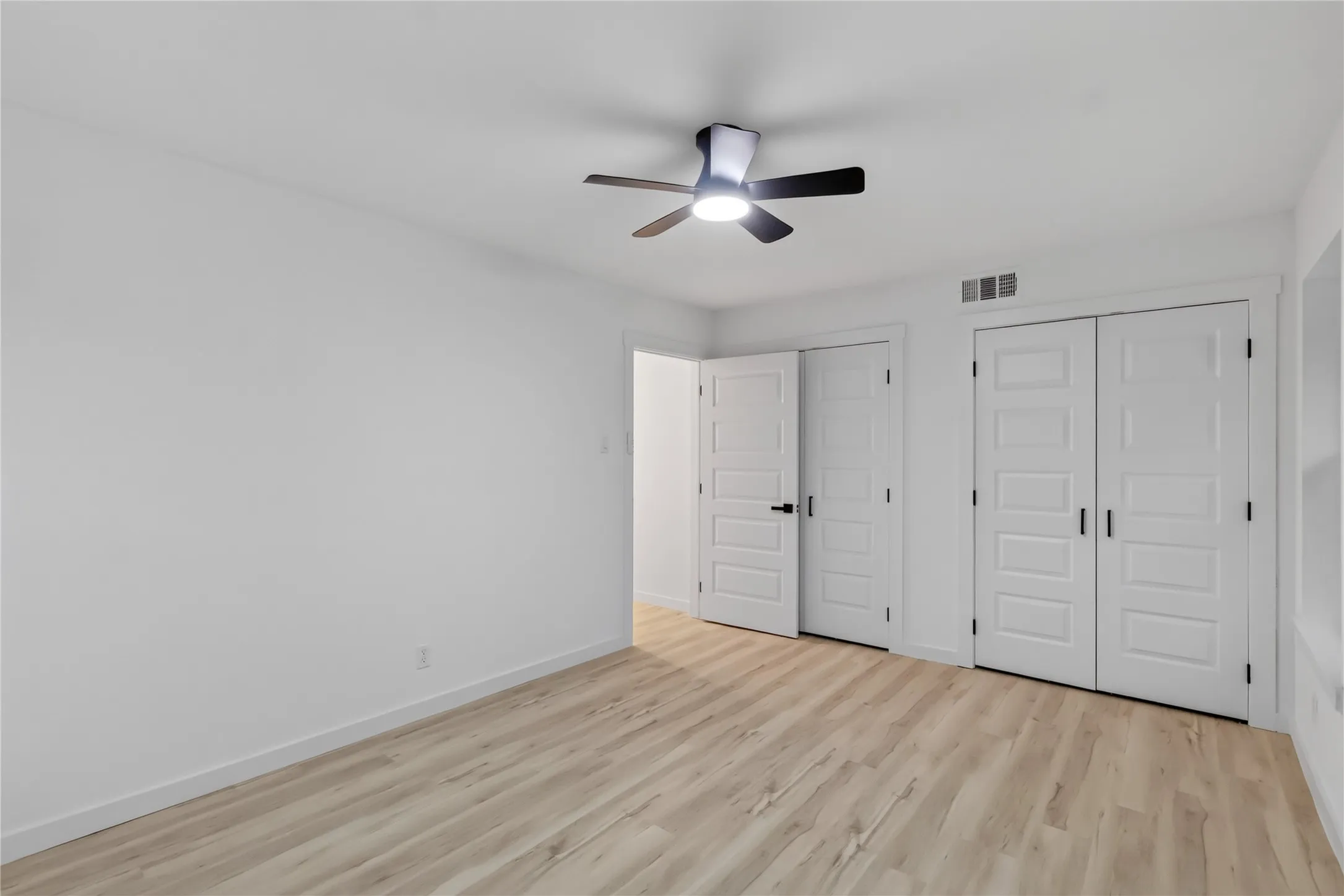 Third Bedroom: Different Angle- Wood-finish flooring, white walls, and a ceiling fan with integrated lighting