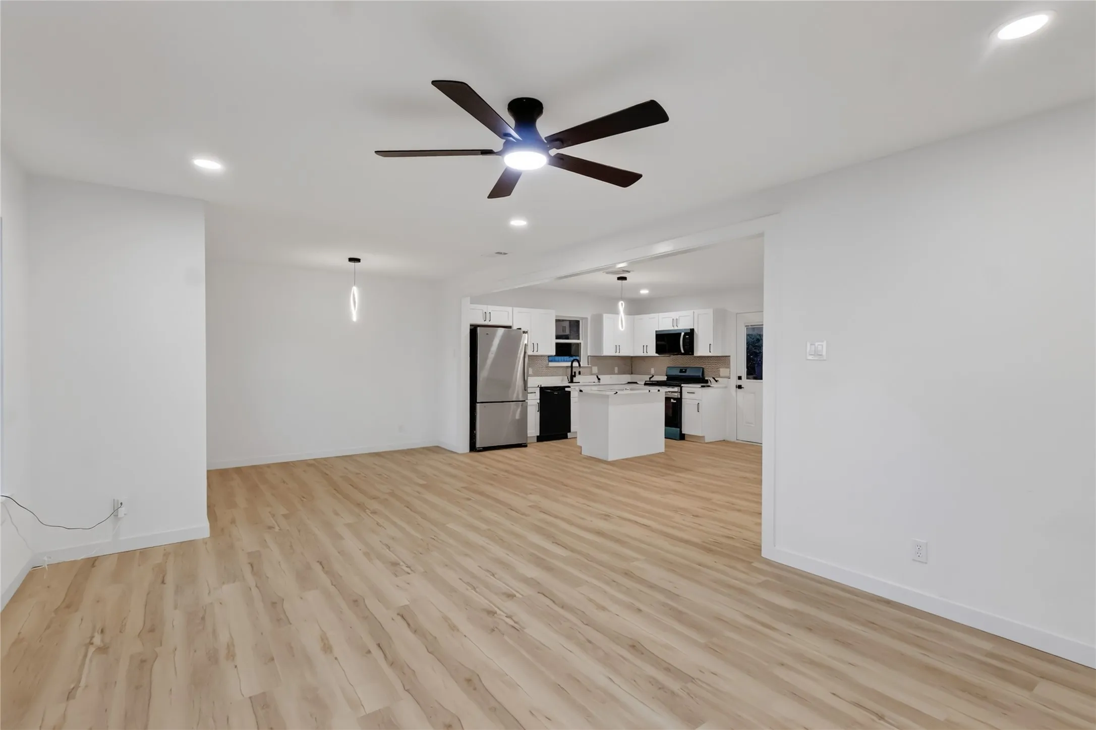 Open concept living area featuring wood-finish flooring, recessed lighting, and a modern ceiling fan