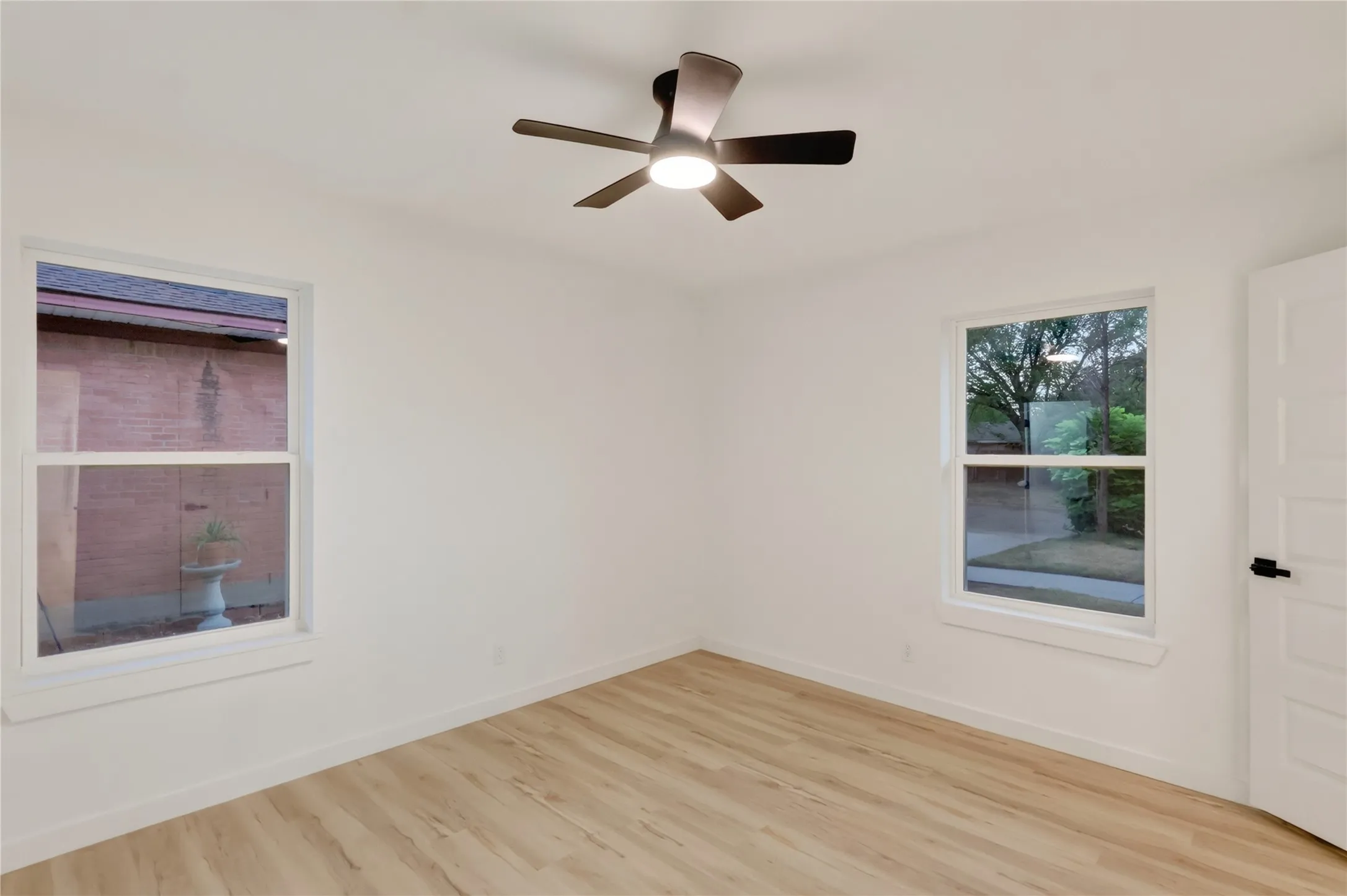 Light wood-finish flooring, white walls, and a contemporary ceiling fan