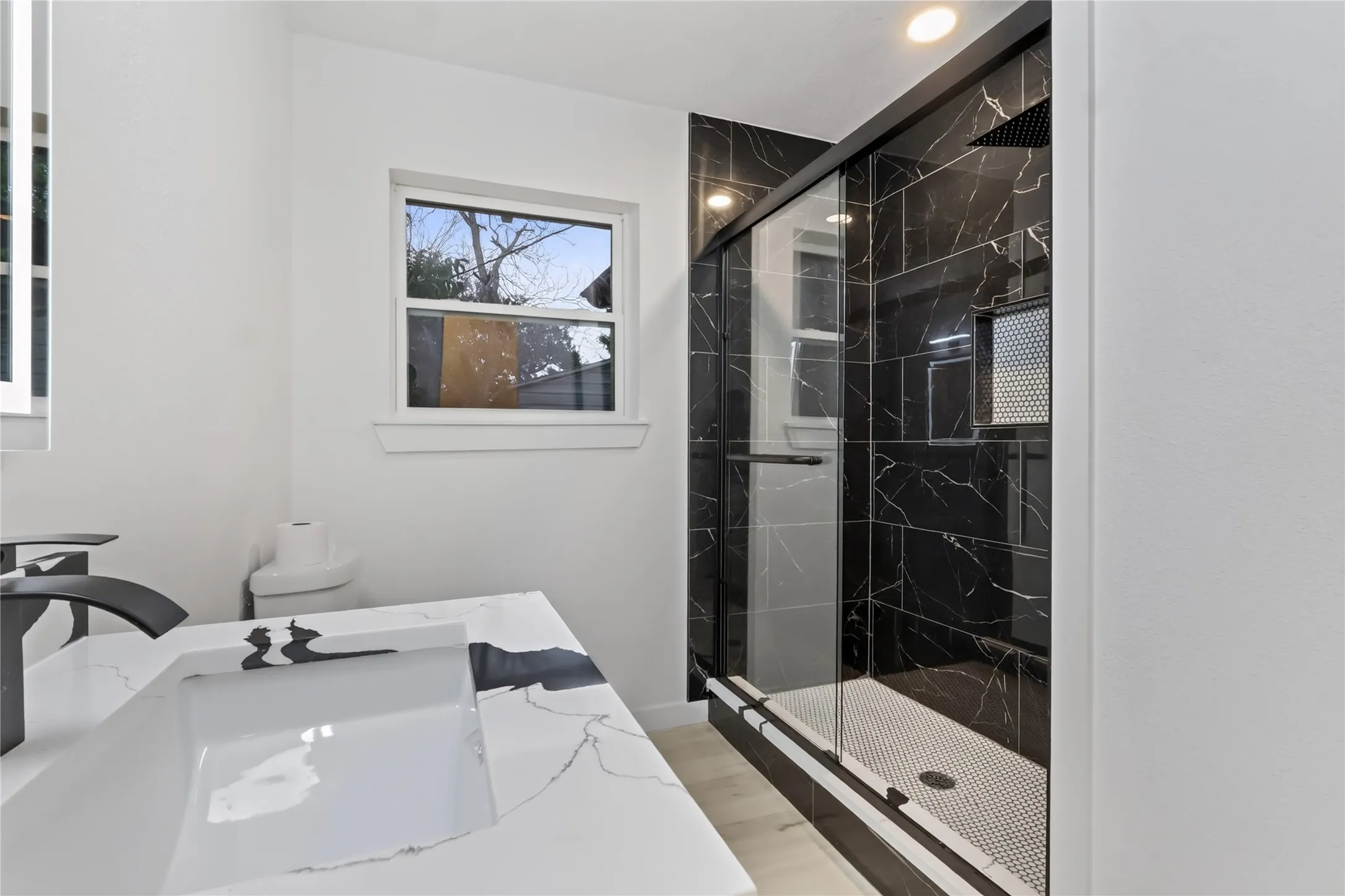 Modern bathroom with a white vanity featuring a rectangular integrated sink and matte black faucet