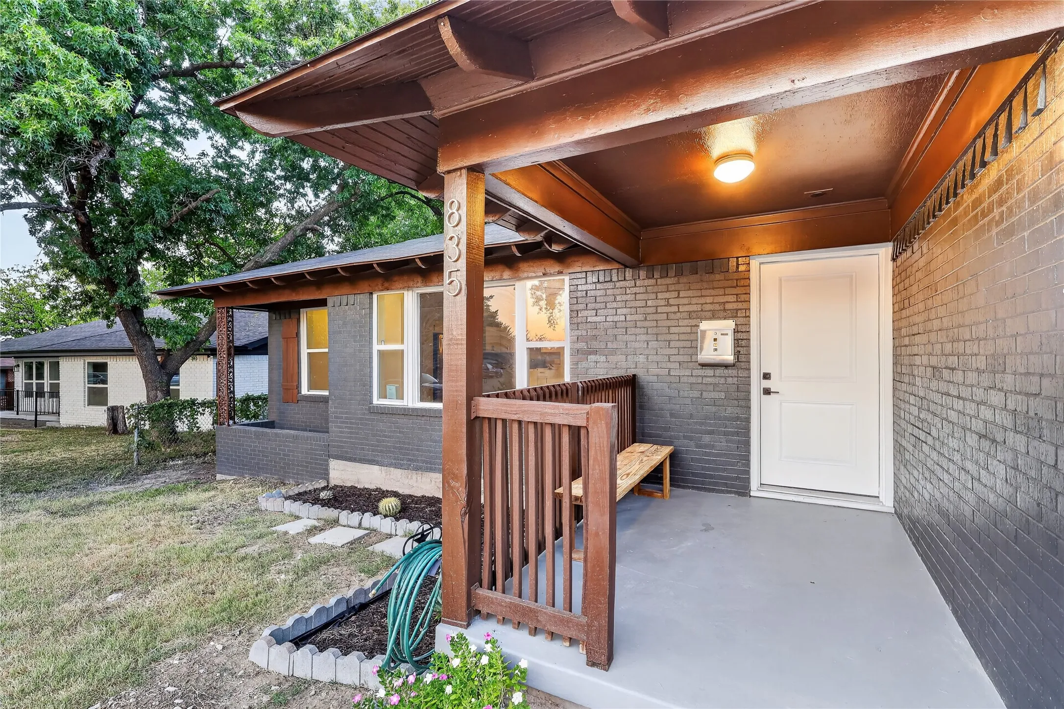 Brick exterior with a covered porch, wood-finish columns, and a white entry door