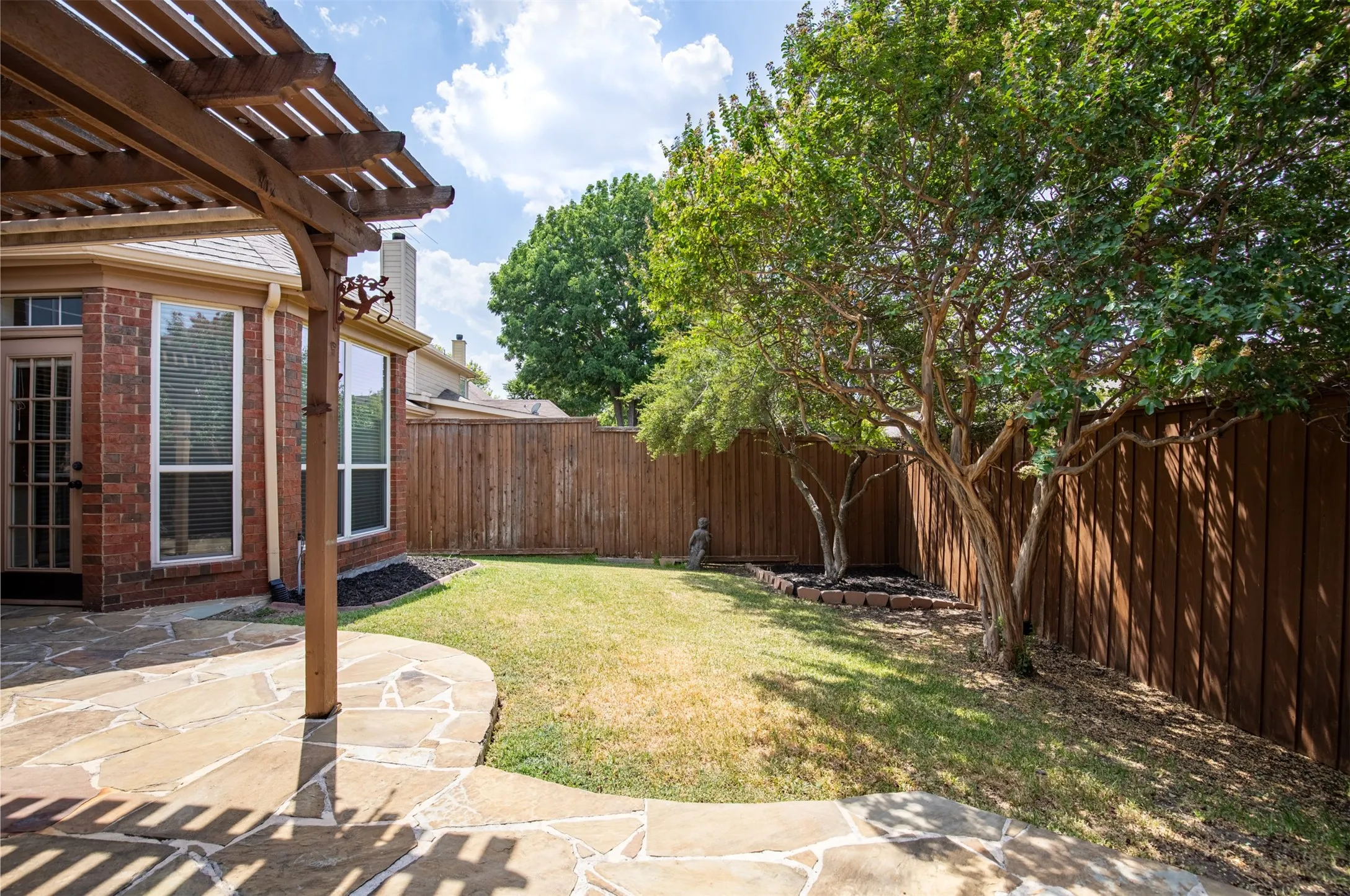 Expansive backyard surrounded by fencing and mature trees offering privacy.