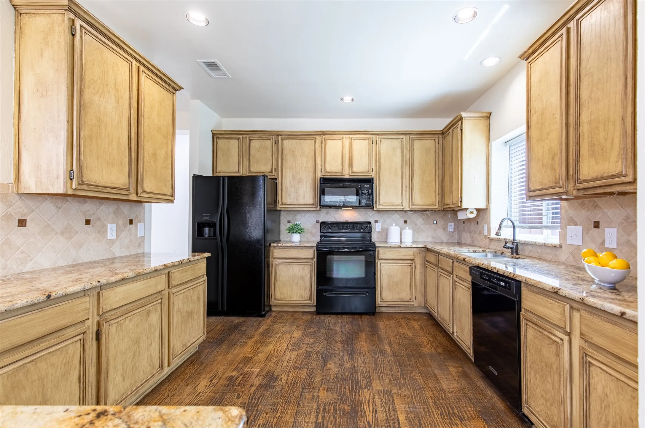 Kitchen showcasing black appliances and refrigerator that conveys.