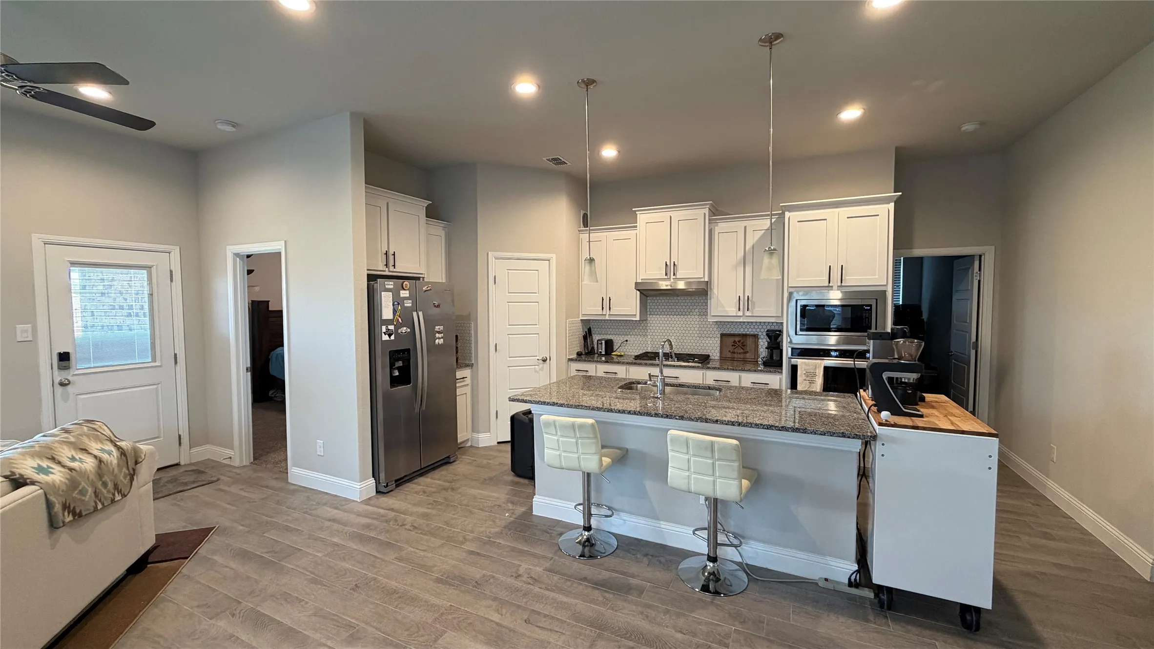 Kitchen featuring white cabinetry, stainless steel appliances, a granite-finish island, recessed lighting, and wood-finish flooring