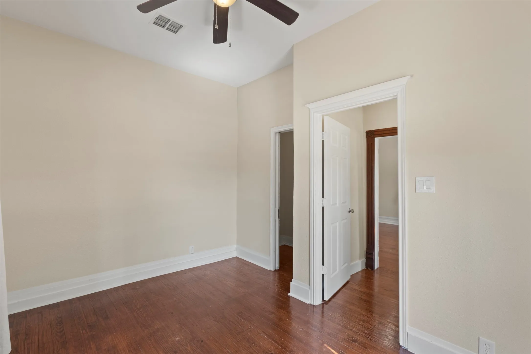 Hardwood-style flooring, white trim details, and a ceiling fan with integrated lighting