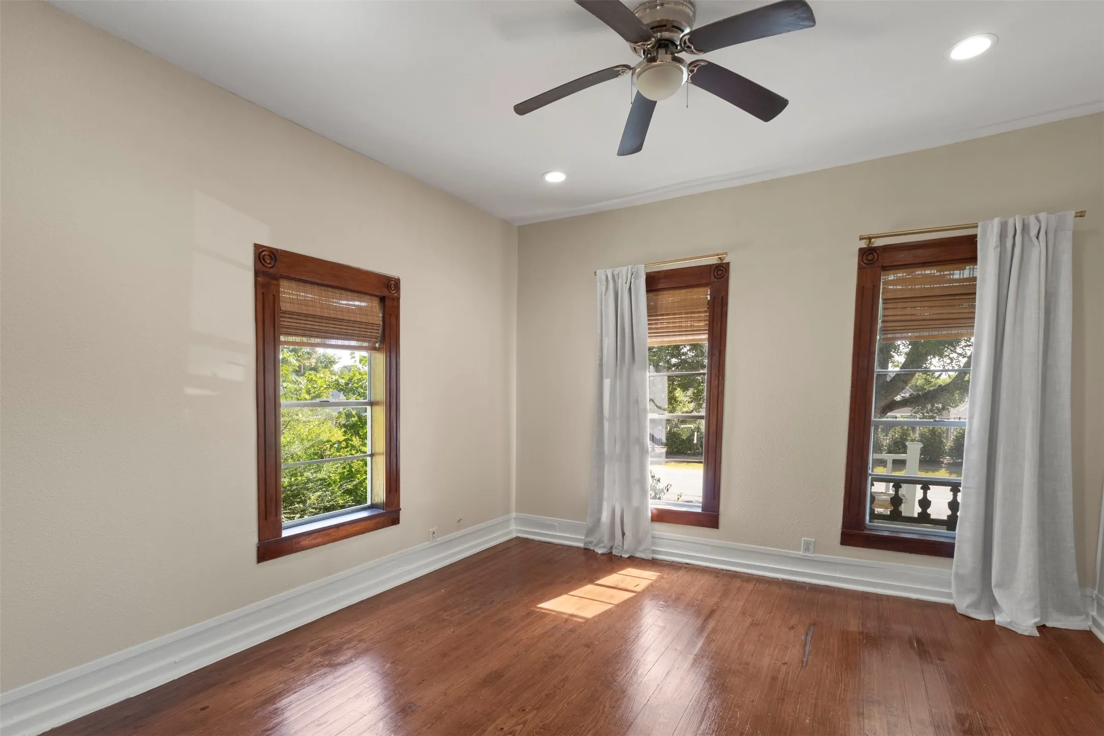Hardwood flooring, recessed lighting, ceiling fan, and multiple windows with wood trim