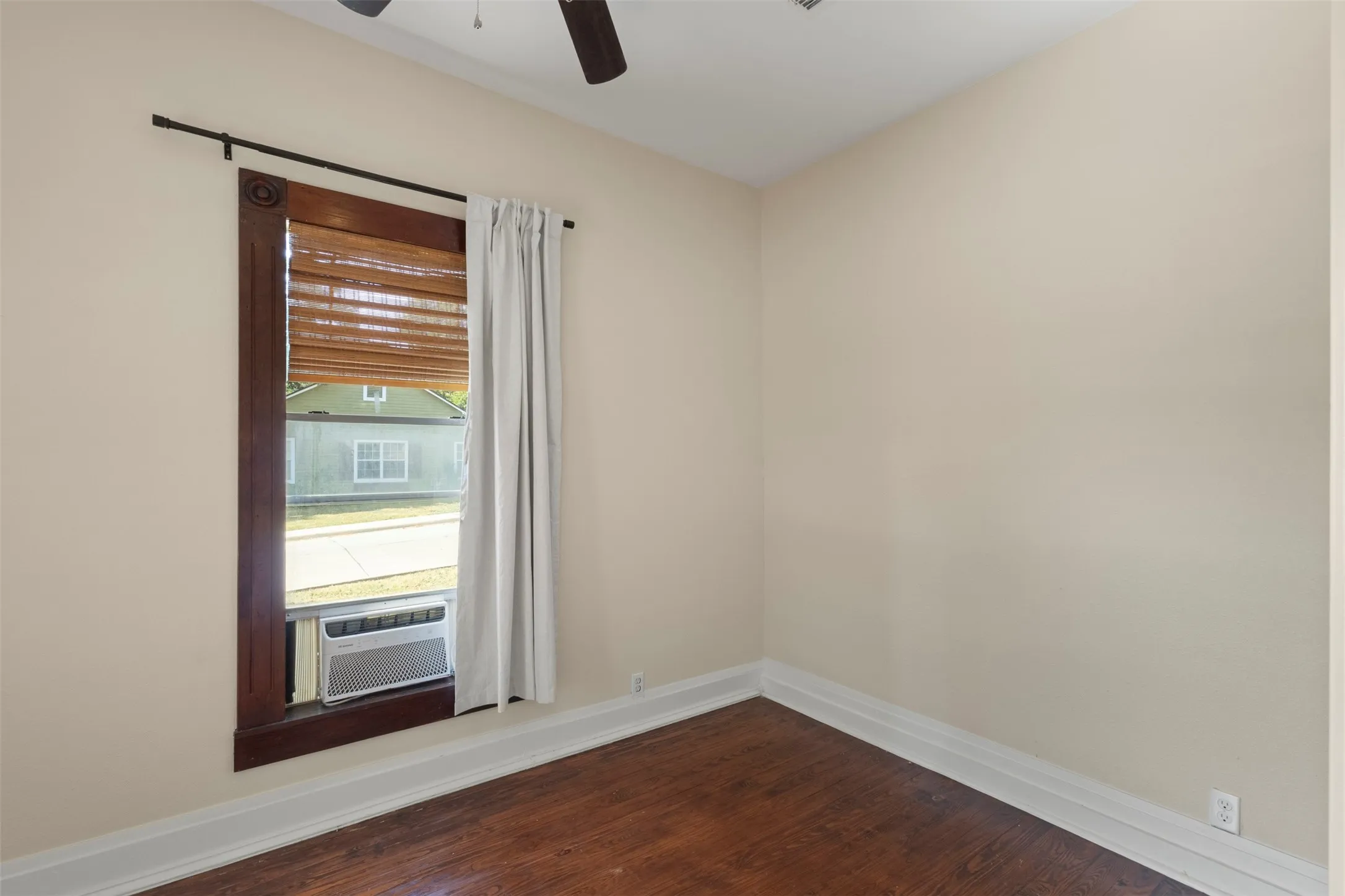 Hardwood-style flooring, light-toned walls, and a ceiling fan with light fixture
