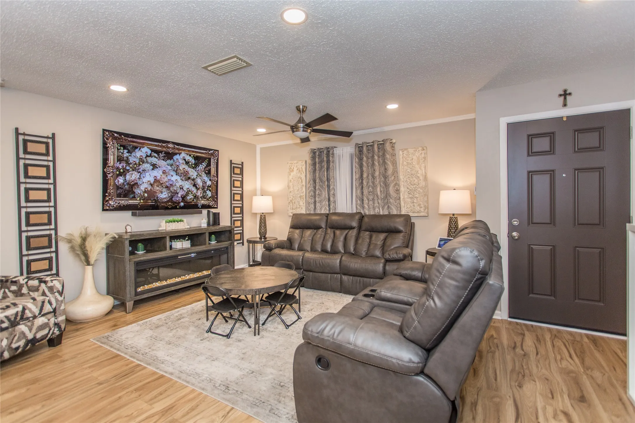 Spacious living area featuring wood-finish flooring, recessed lighting, and a dark paneled entry door