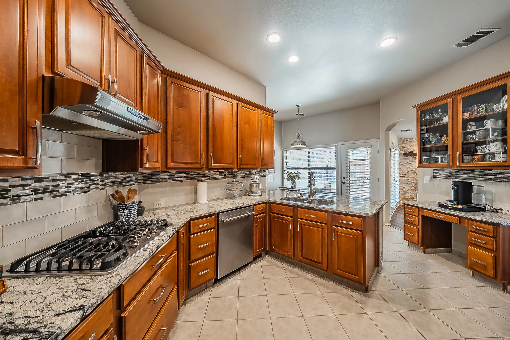 Kitchen featuring wood cabinetry, light-toned countertops, a gas range, stainless steel appliances, and a tiled backsplash