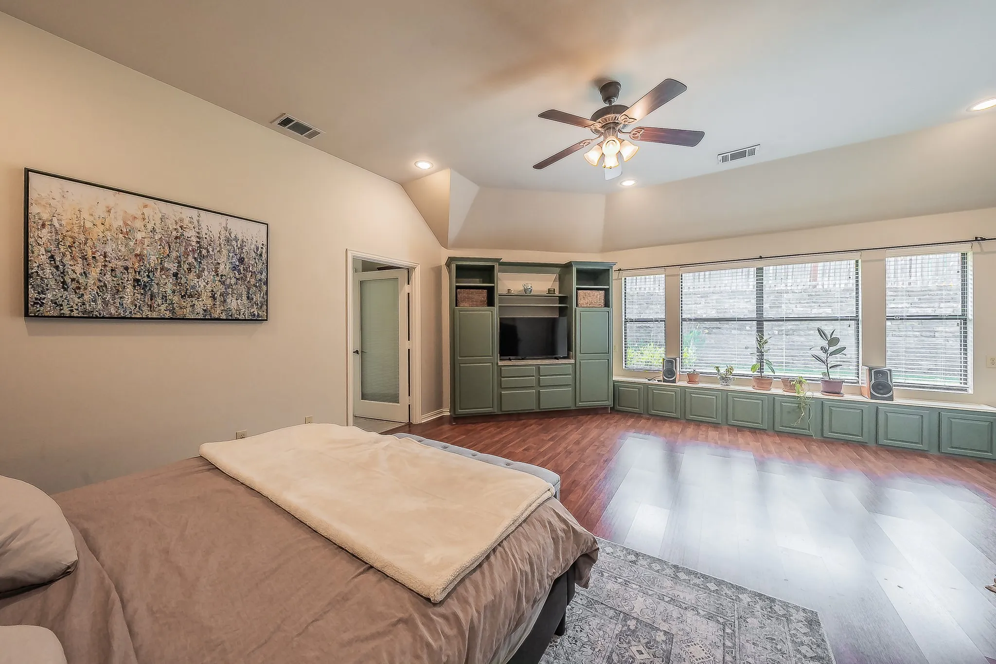Vaulted ceilings, wood-finish flooring, built-in media cabinetry, and a ceiling fan with integrated lighting