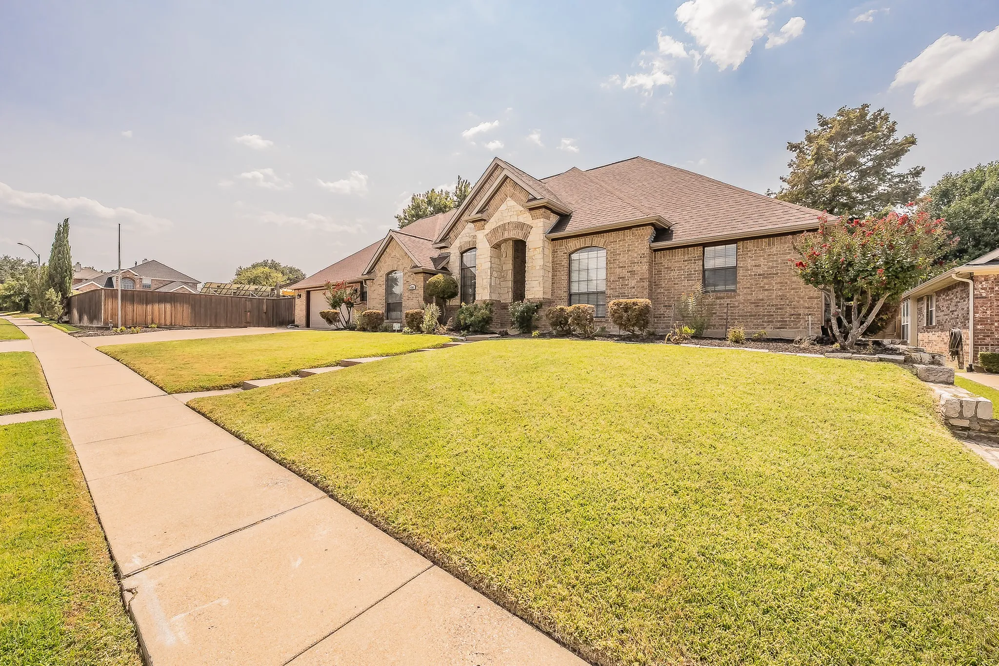 Brick exterior with stone accents, hip roof, and arched entryway