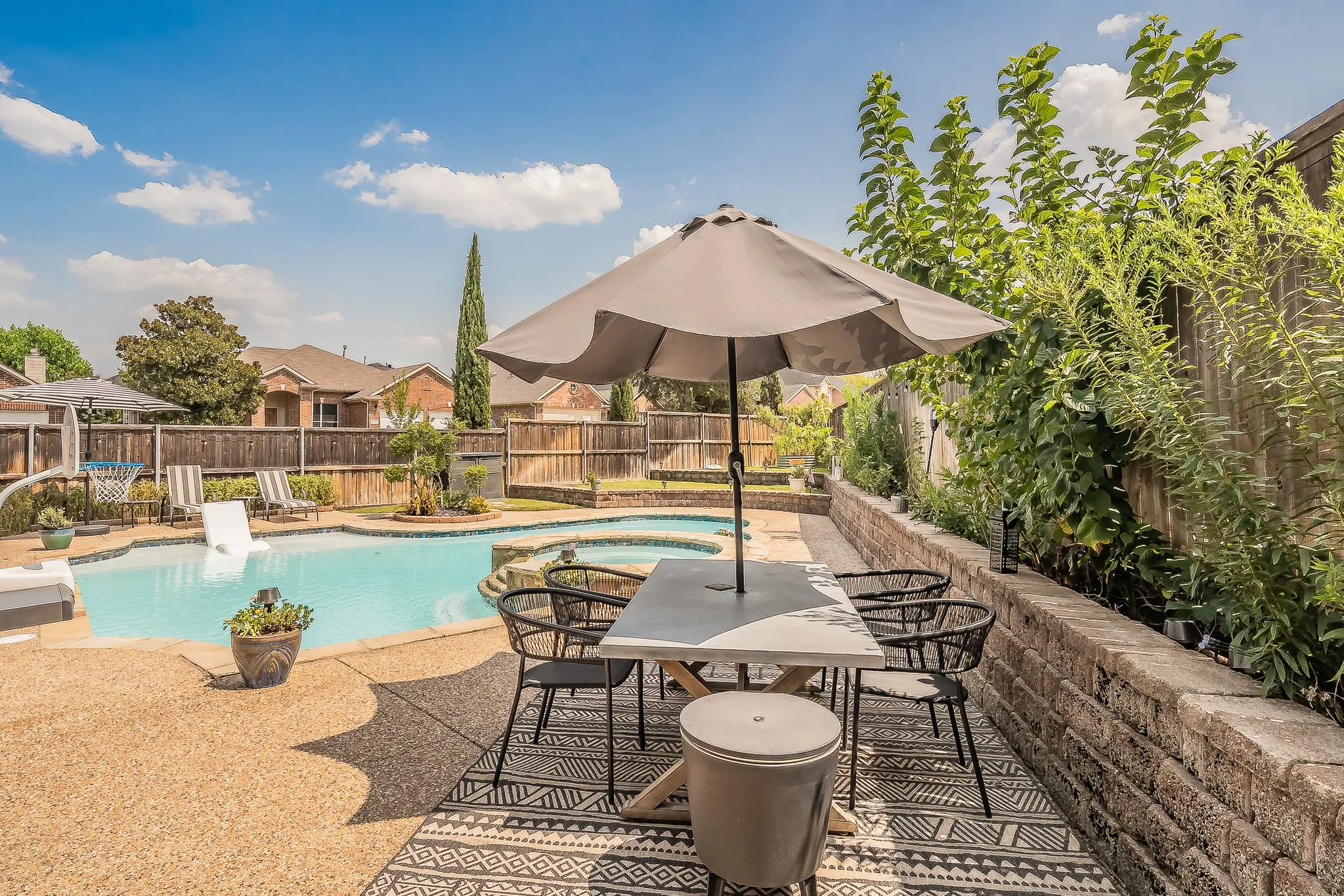 Expansive backyard featuring a freeform swimming pool, integrated spa, and exposed aggregate concrete patio