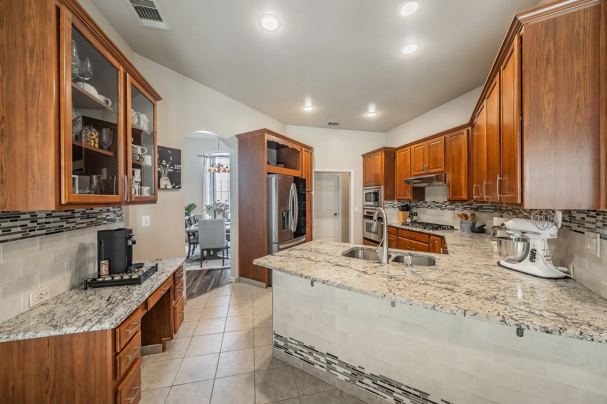 Kitchen featuring wood cabinetry, light-toned countertops, a tile backsplash, and recessed lighting