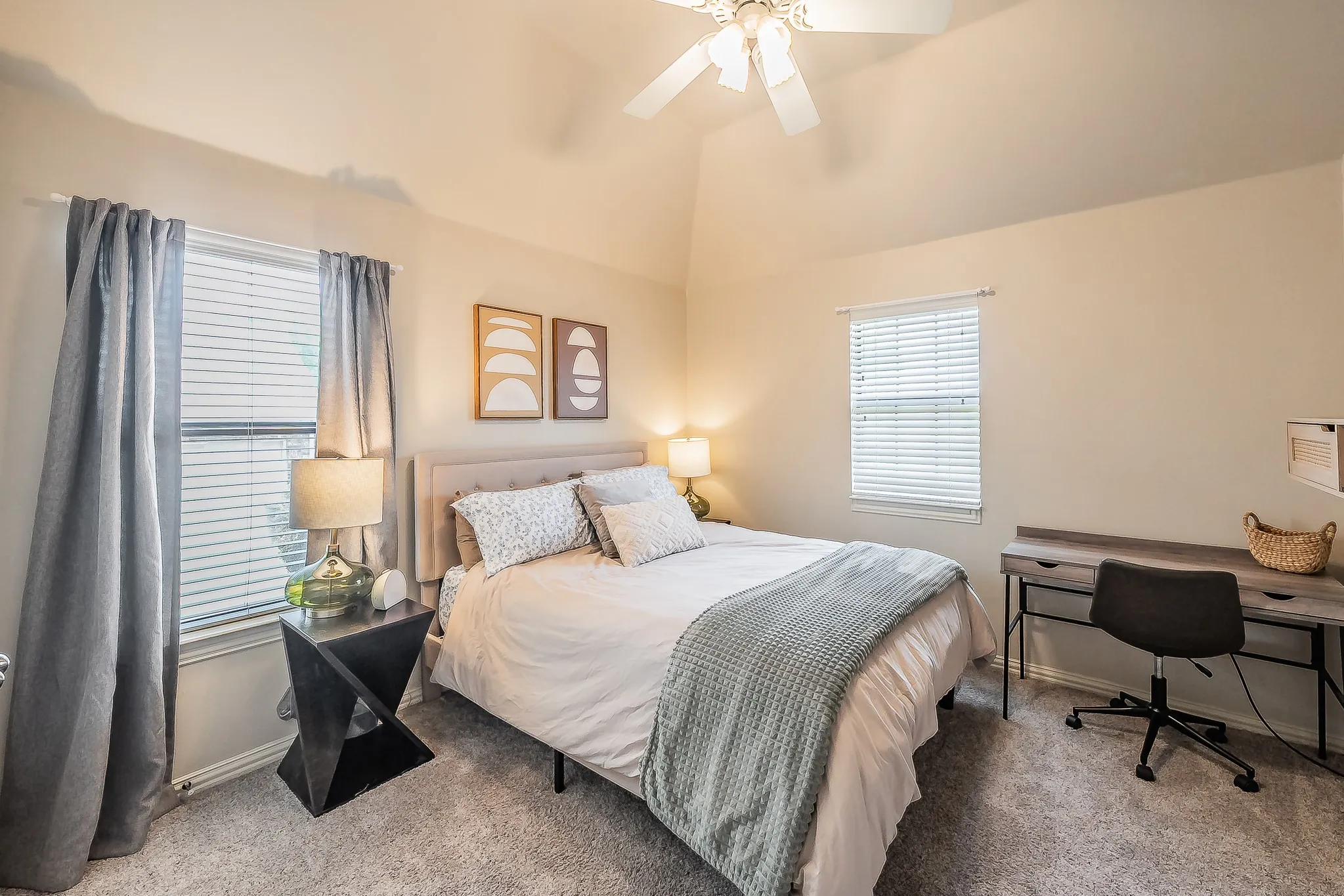 Vaulted ceiling with a ceiling fan, two windows with blinds, and carpeted flooring