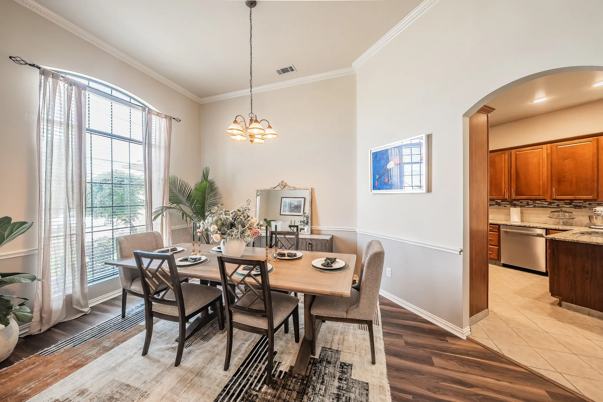 Wood-finish flooring, crown molding, and an arched entryway