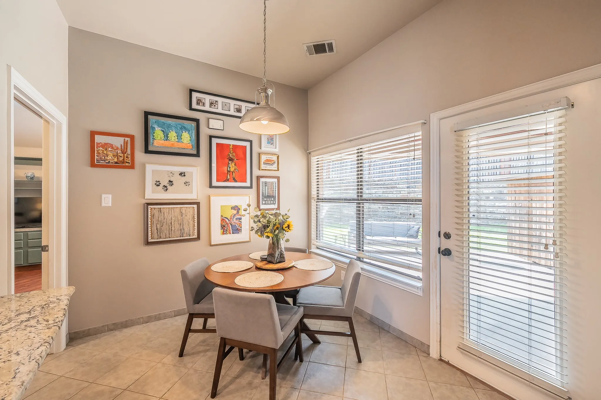 Vaulted ceiling, tiled flooring, granite-finish countertop, pendant light fixture, and abundant natural light
